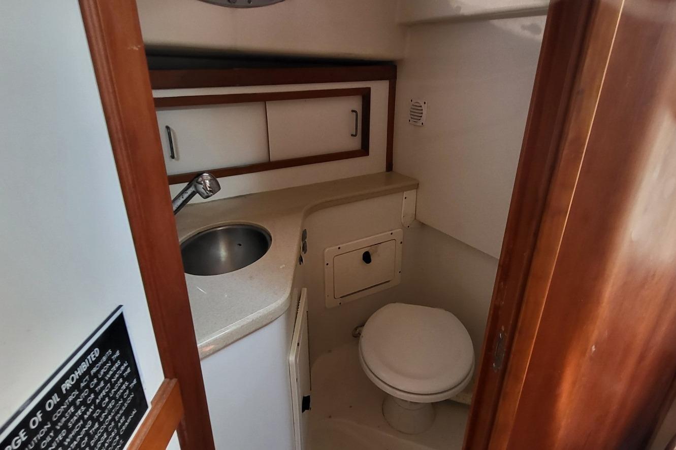 2006 Back Cove 29 boat bathroom with sink, toilet, and storage cabinets.