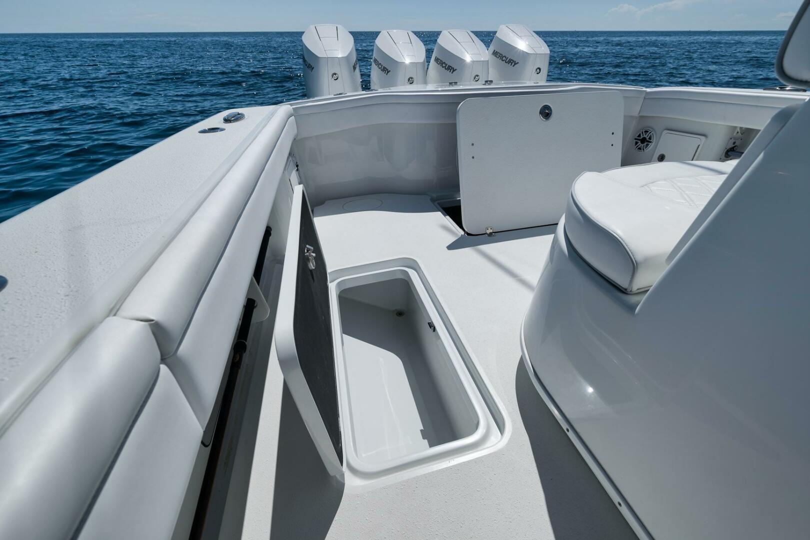 2023 Yellowfin 39 Offshore boat interior with storage and seating, ocean backdrop.