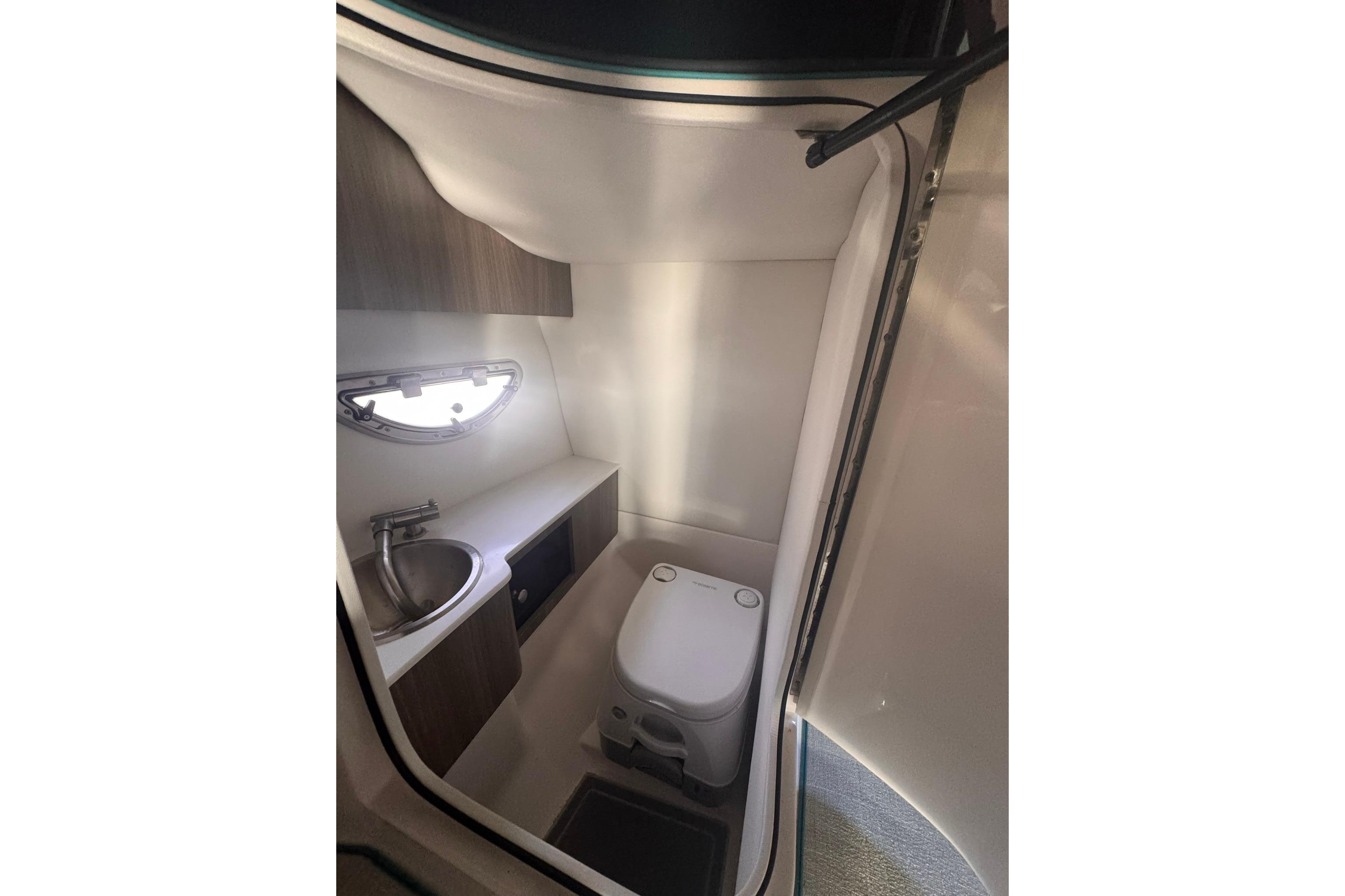 2020 Regal LS6 boat bathroom with sink, toilet, and window.