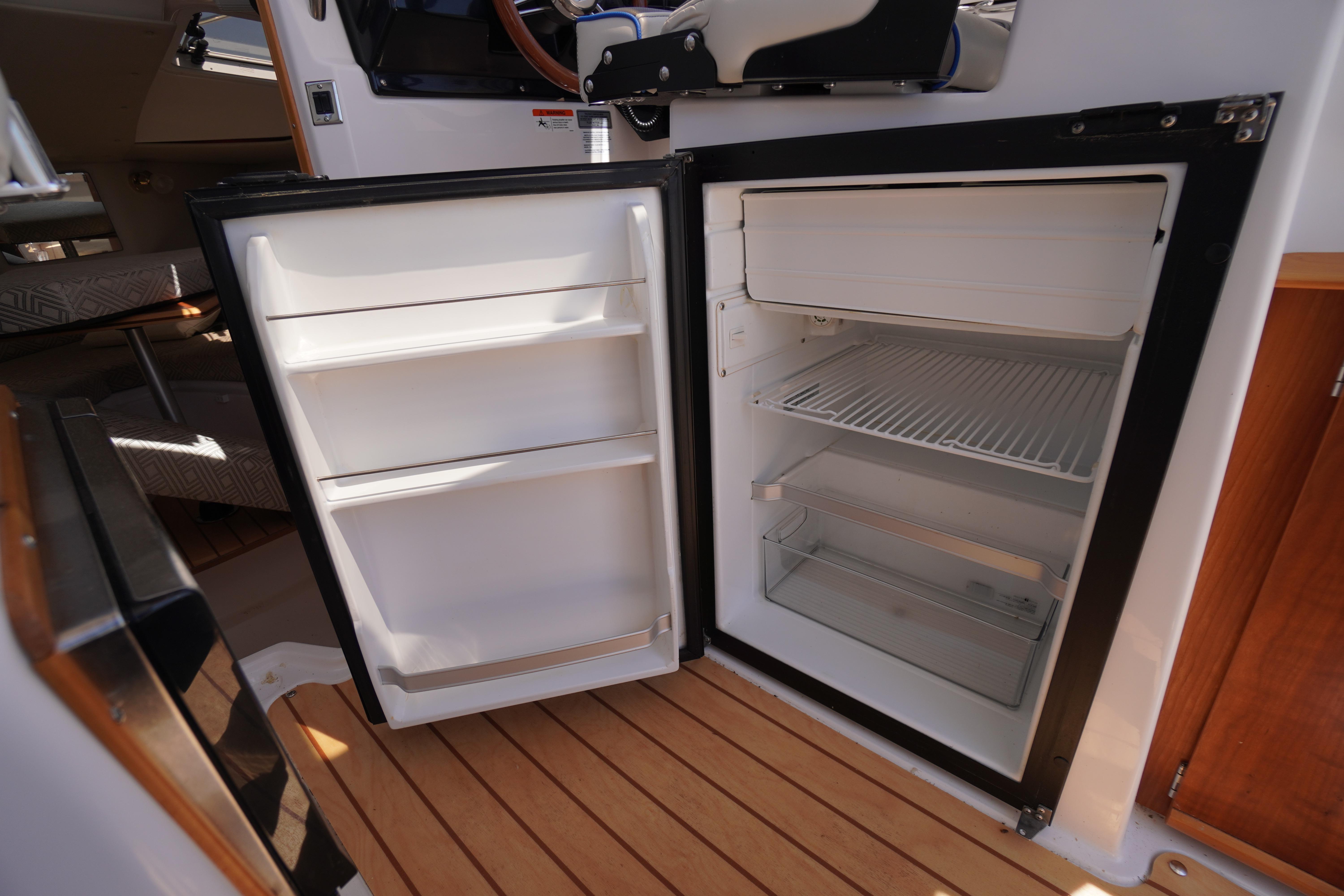 Open refrigerator inside 2019 Cutwater C-242 Sport Coupe boat, showcasing interior storage space.