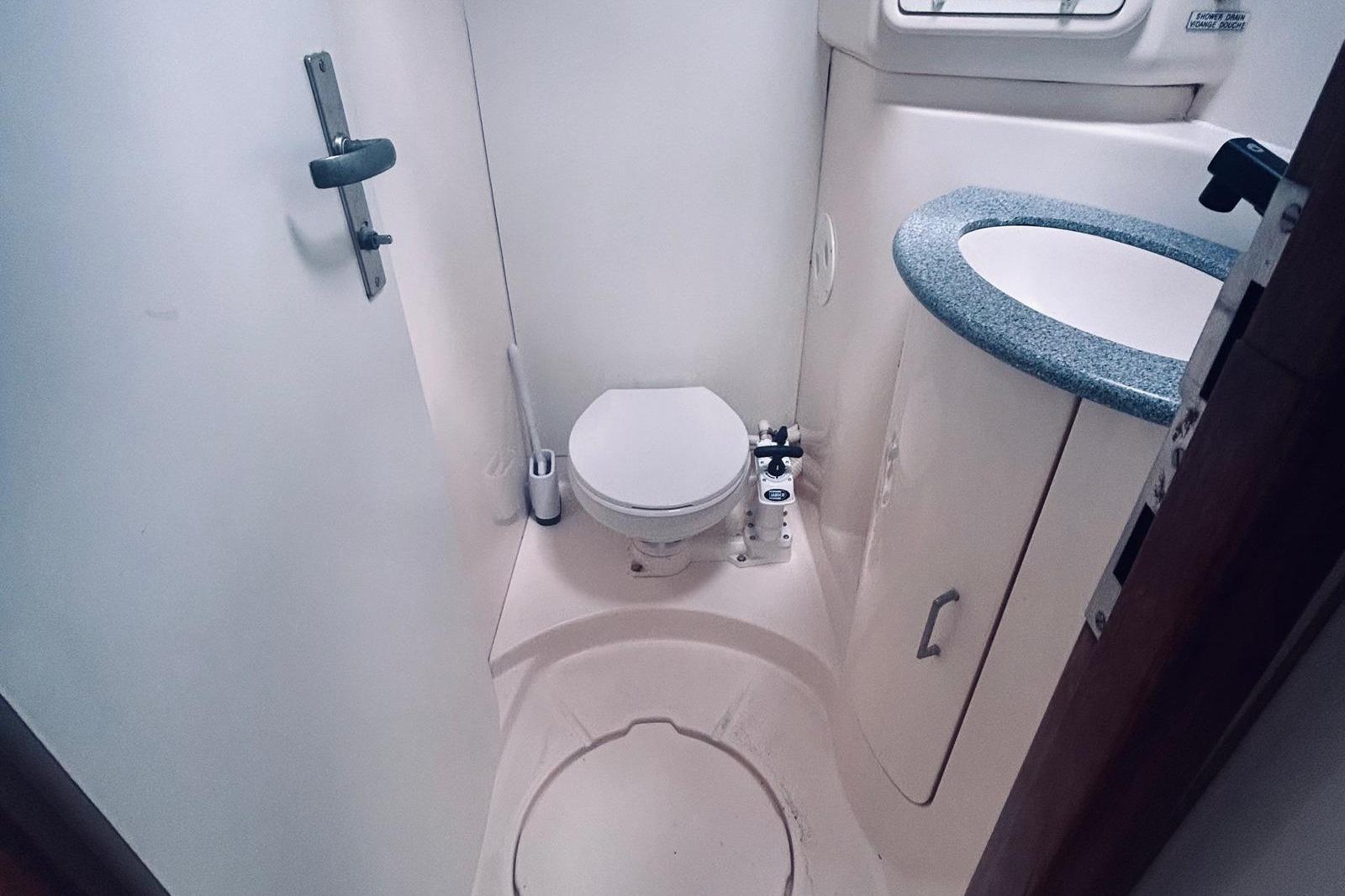 Compact bathroom in a 2001 Robertson & Caine Leopard yacht, featuring a toilet and sink.