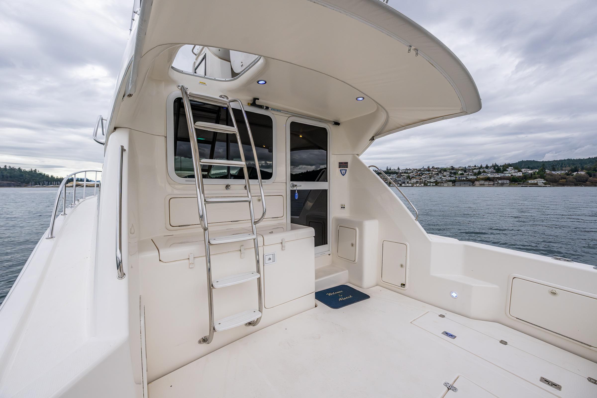 2004 Riviera 37 Flybridge yacht deck with ladder, overlooking serene waters and distant shoreline.