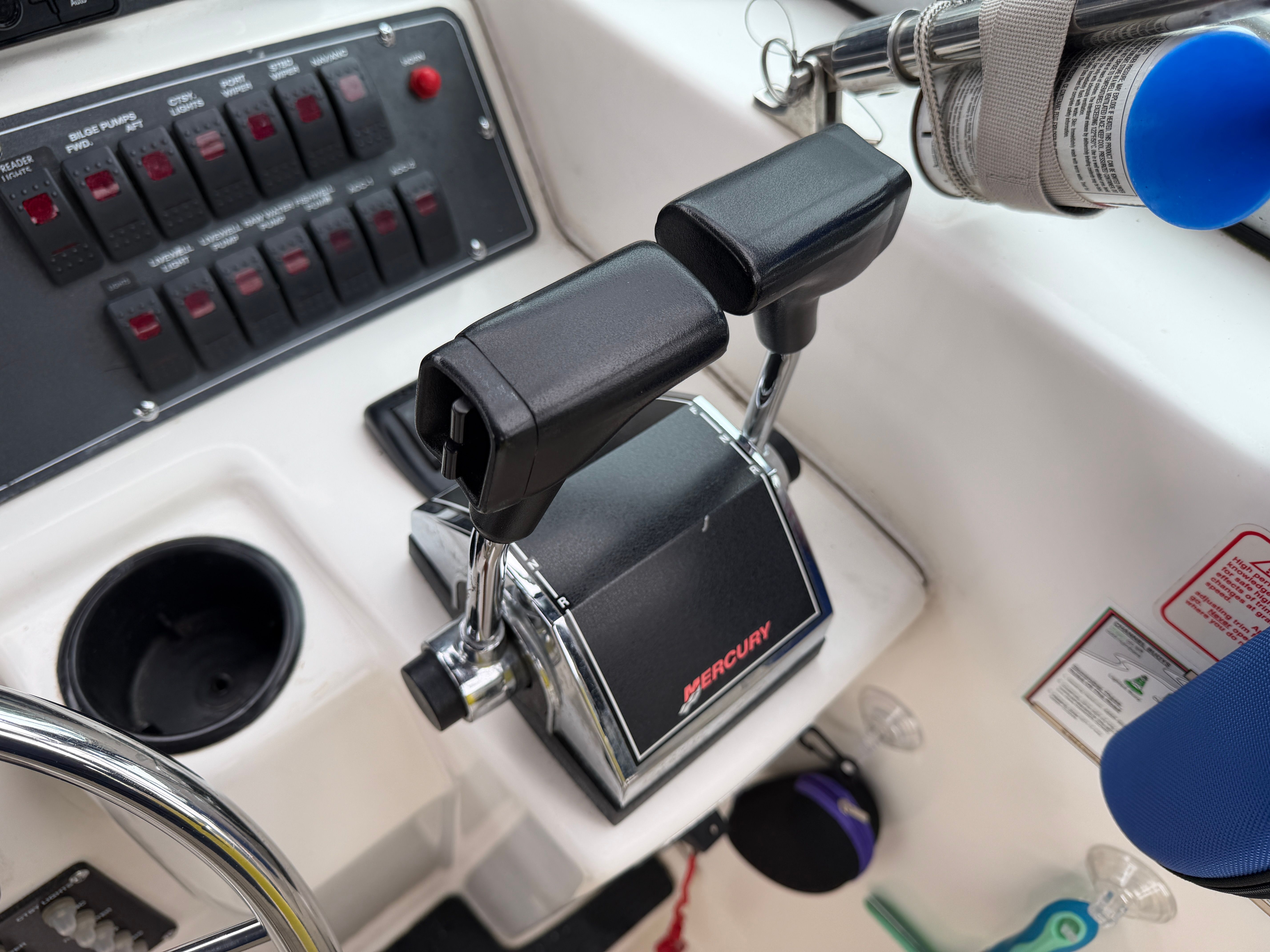 Close-up of a boat's control console with dual throttle levers and switches.