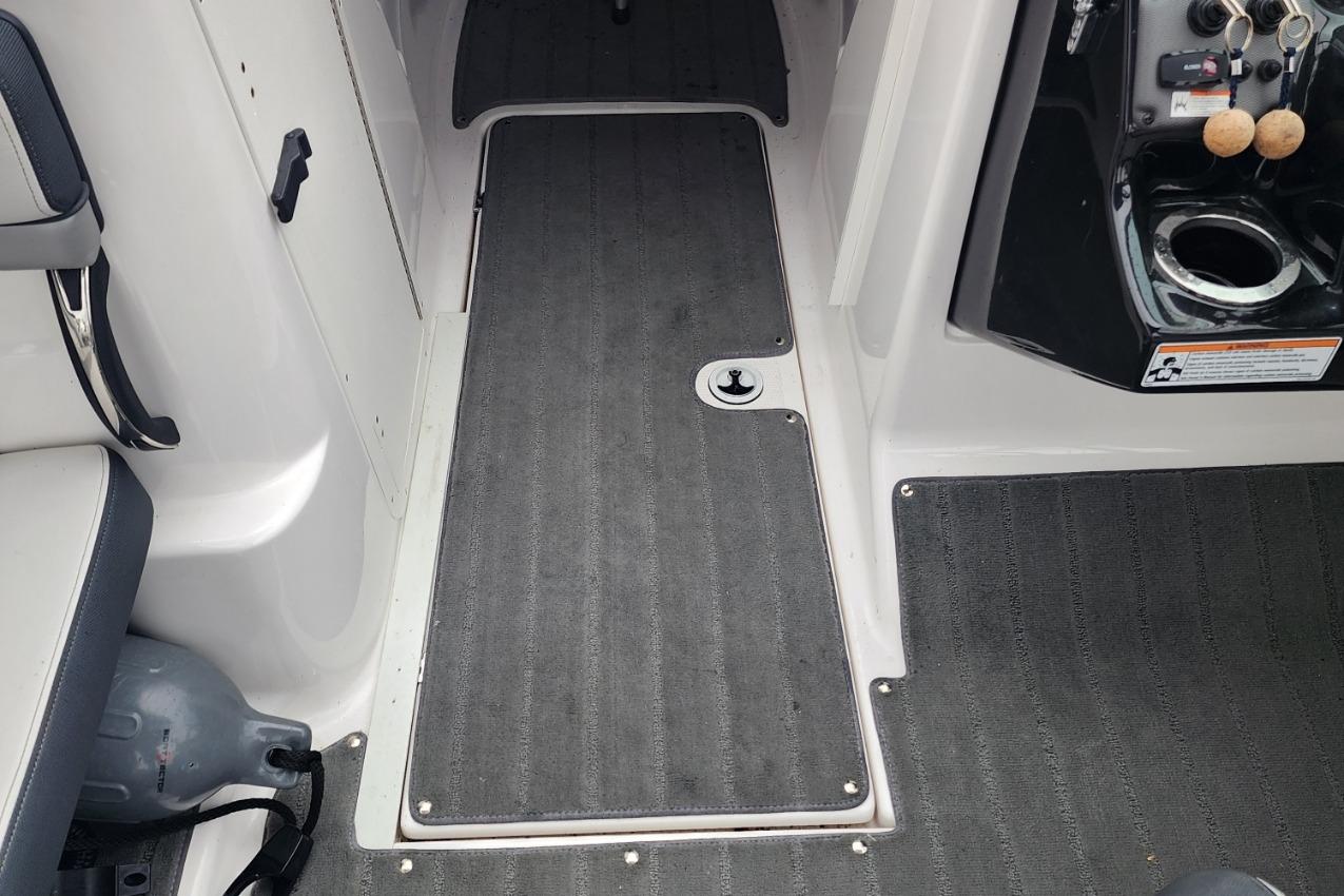 Interior view of a 2015 Yamaha Boats 212X, featuring gray carpet and seating area.