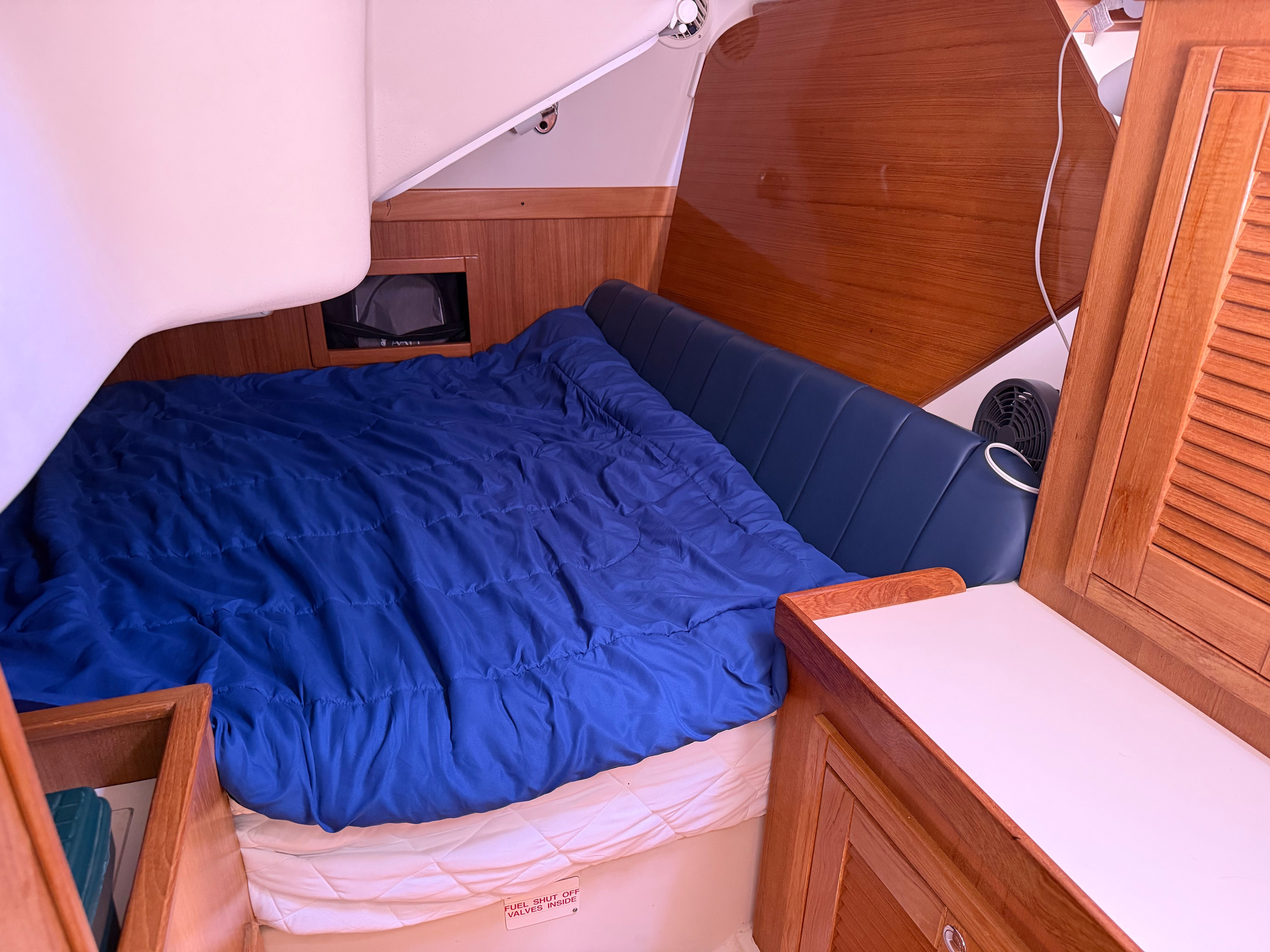 Interior of a Catalina 350 with a blue bed and wooden furnishings.