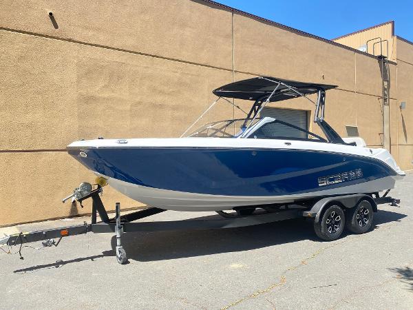 2025 Scarab 235 SE boat on trailer, blue and white design, parked outdoors.