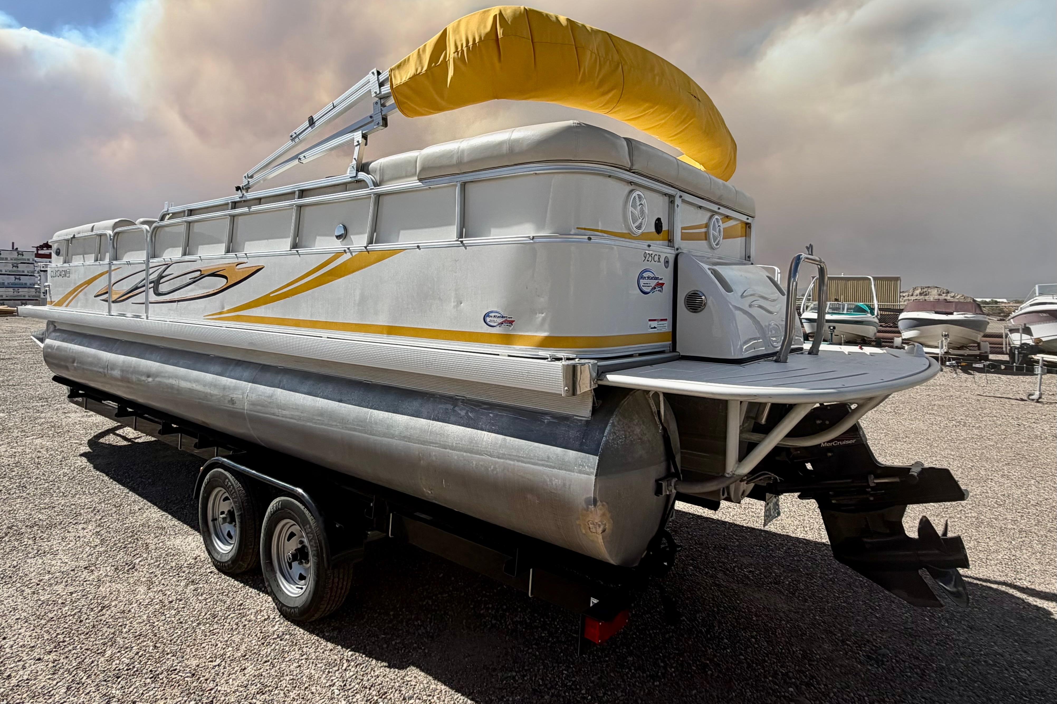 2006 South Bay 925CR pontoon boat with yellow canopy on a trailer, parked outdoors.