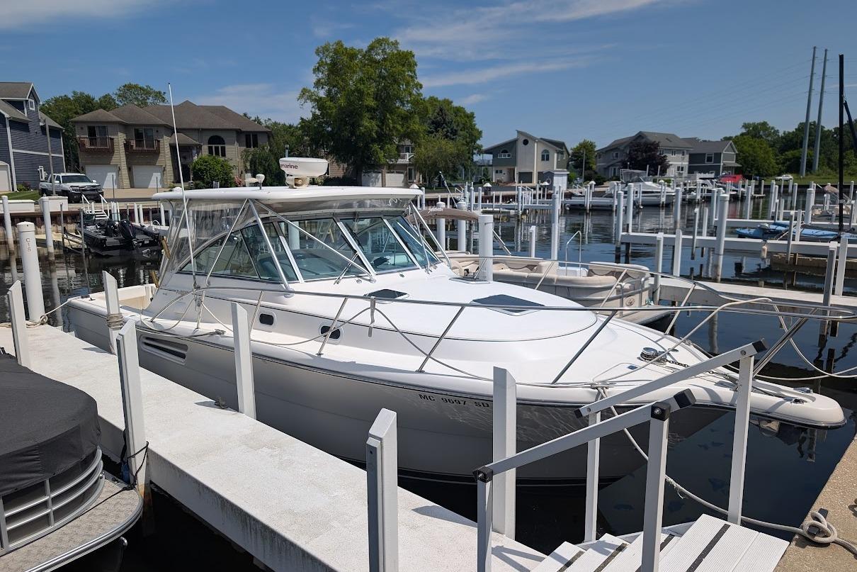2000 Pursuit 3400 Express boat docked at a marina, surrounded by other boats and waterfront homes.