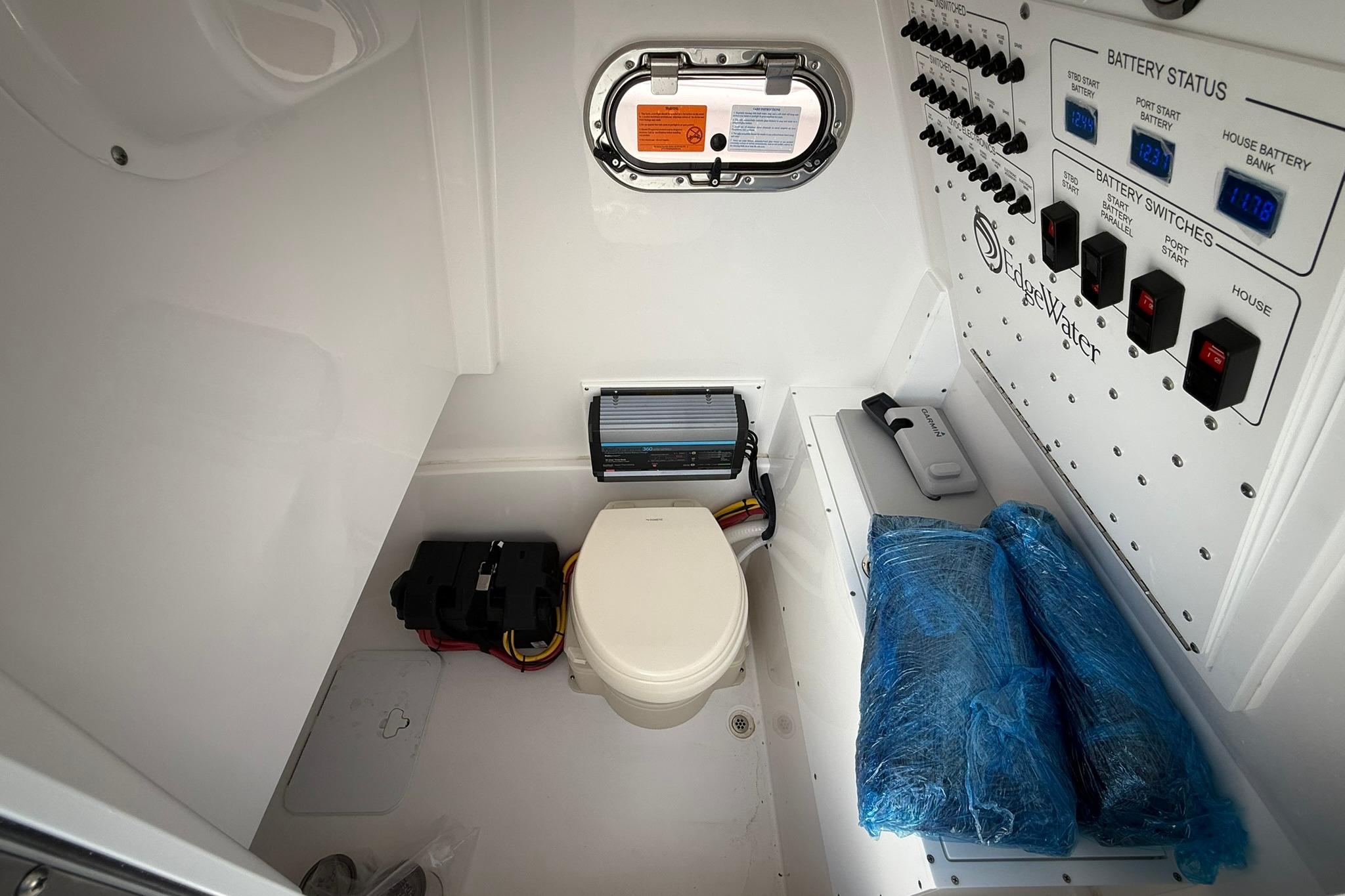 Interior of 2026 Edgewater 250CC boat featuring control panel and compact toilet.