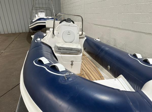 2024 Apex A-13 Deluxe Tender boat with blue and white design in storage.