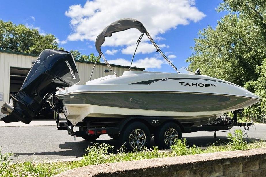 2026 Tahoe 2150 boat on trailer, parked outdoors under a clear blue sky.