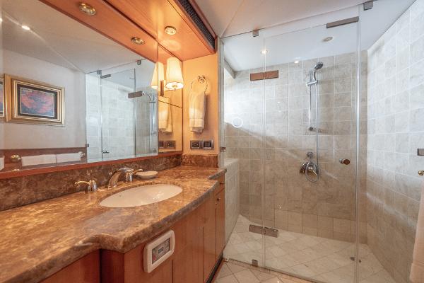 Luxurious bathroom in 2001 Grand Harbour 76 yacht with marble countertop and glass shower.