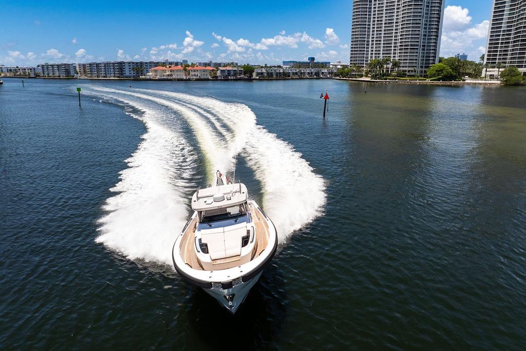 2021 Bluegame BG 42 yacht cruising on a sunny day near waterfront buildings.