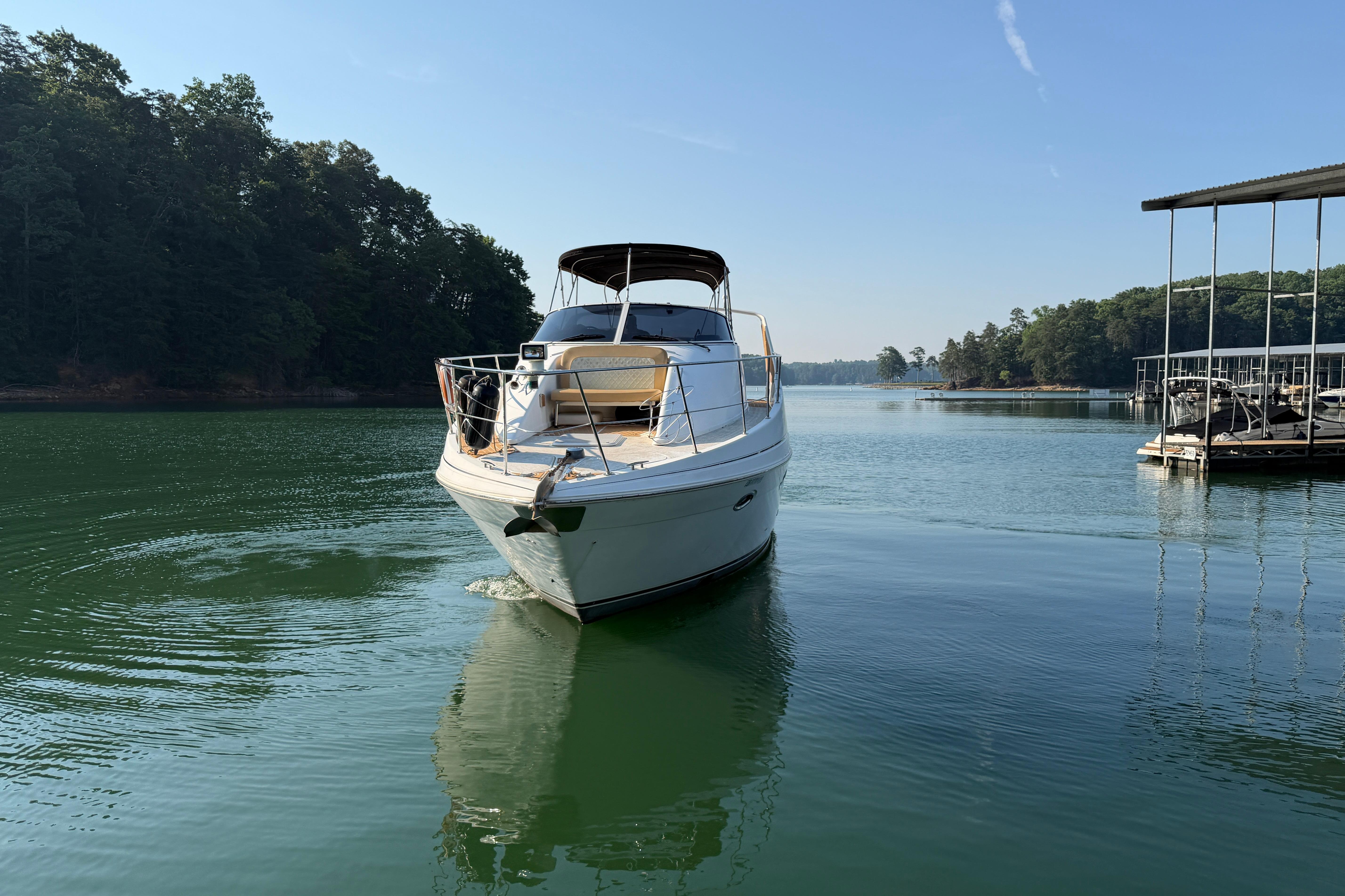 2003 Carver 350 Mariner yacht cruising on a serene lake with lush green surroundings.
