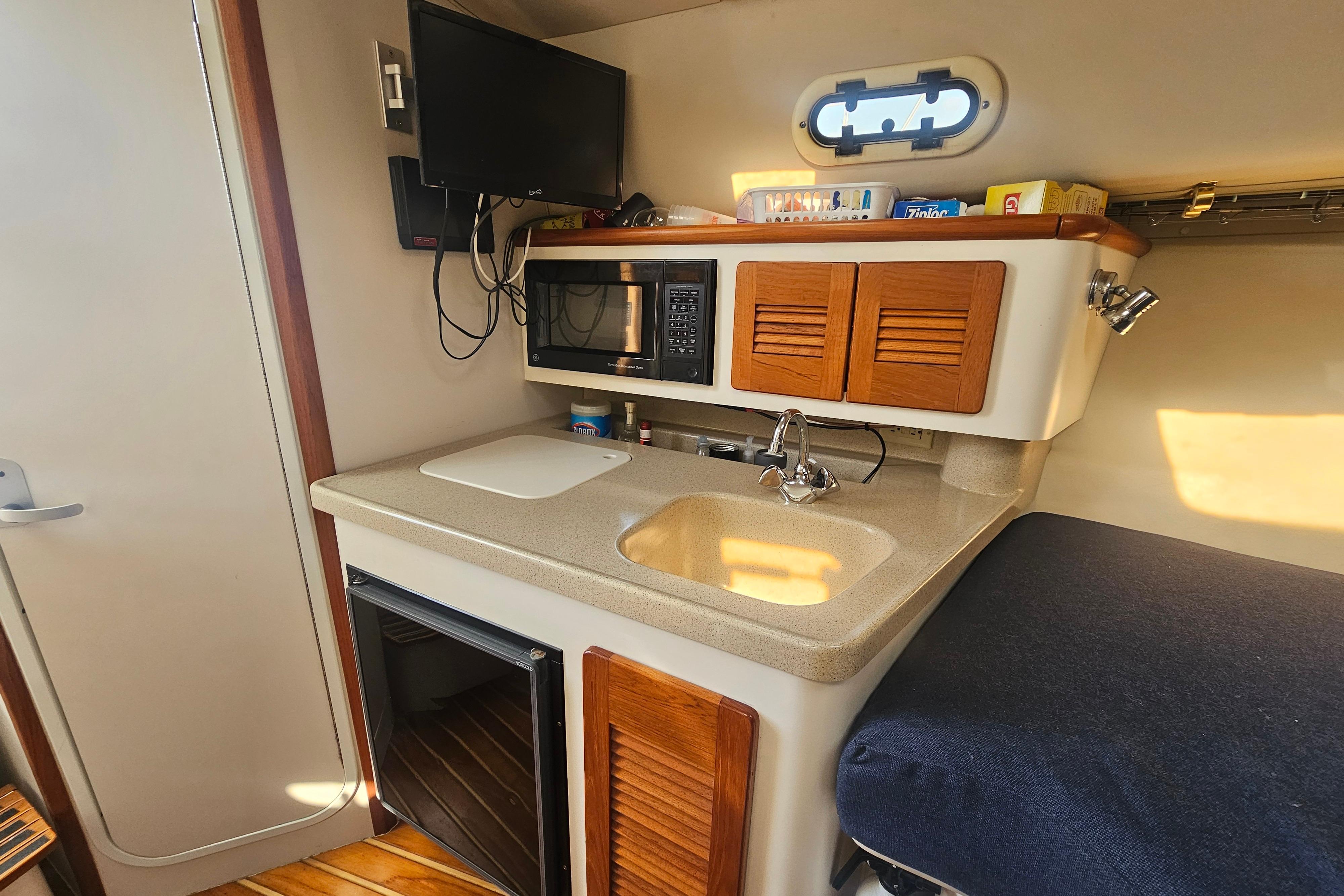 2001 Pursuit 3000 Express boat interior with kitchenette, sink, microwave, and storage cabinets.