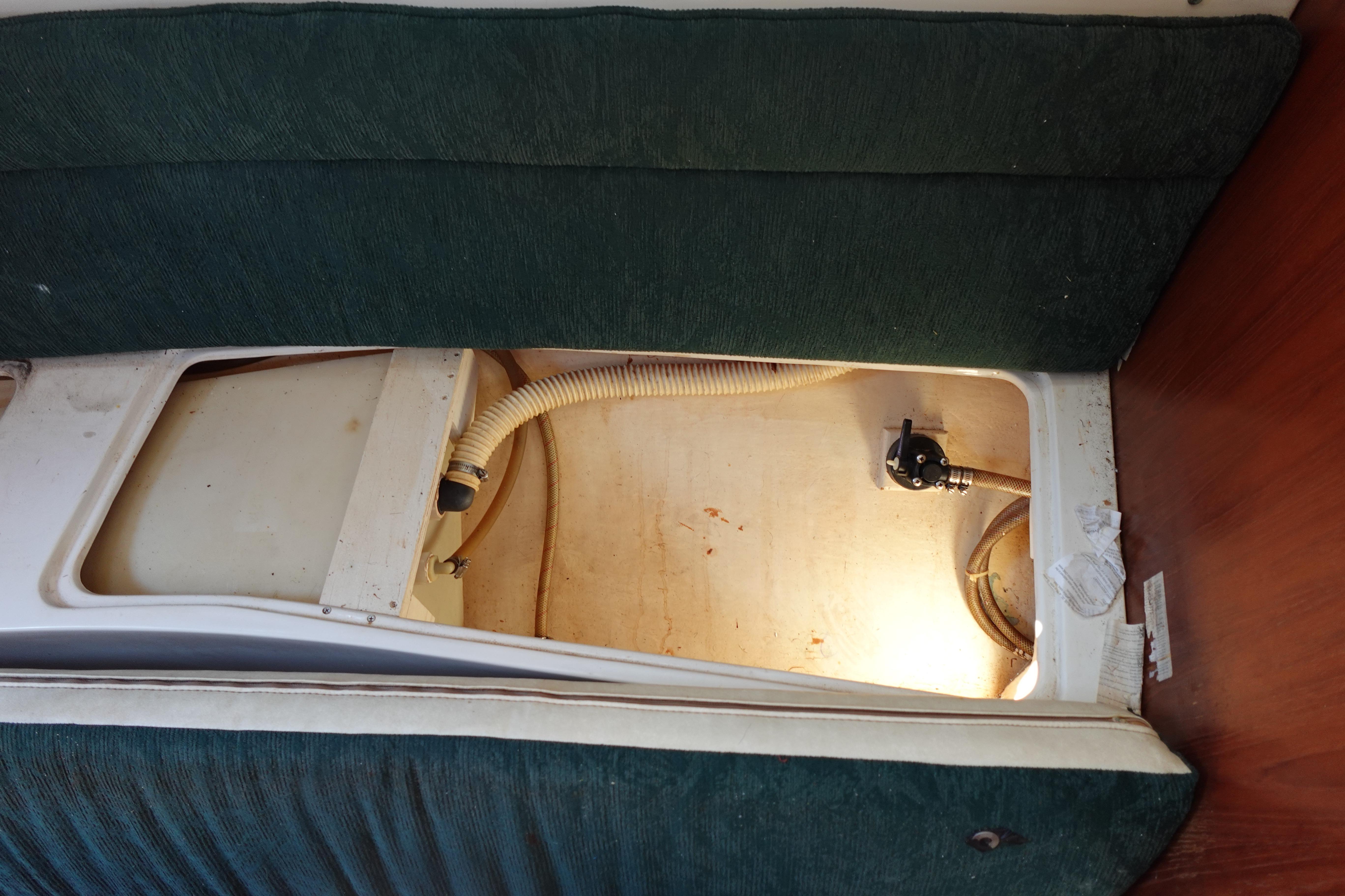 Interior view of a 1997 Catalina 28 sailboat showing storage compartment and plumbing.