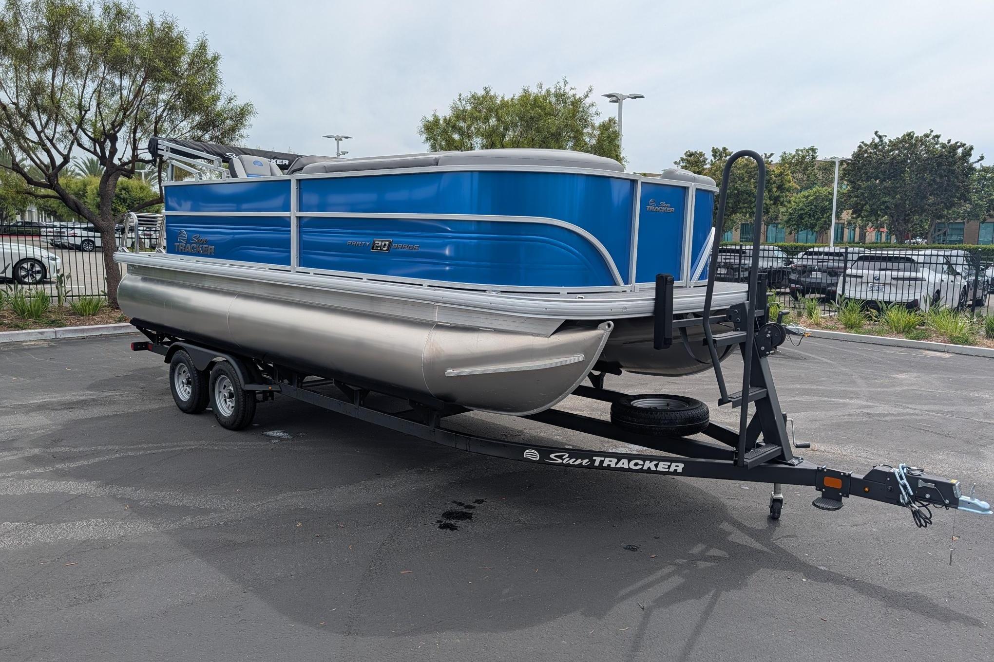 2026 Sun Tracker Party Barge 20 DLX pontoon boat on trailer in parking lot.