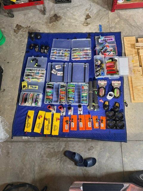 A variety of fishing lures and accessories spread out on a blue blanket.