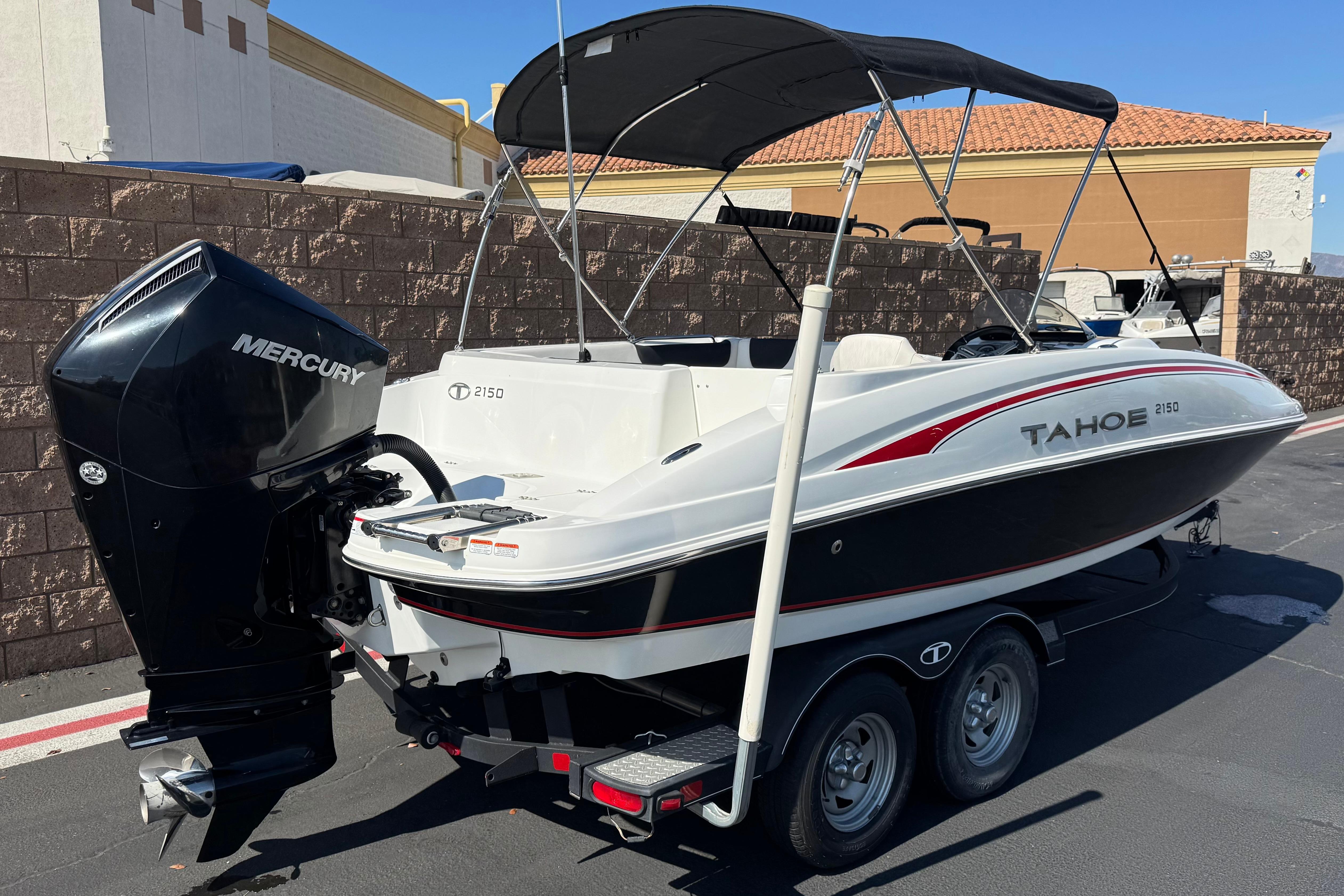 2019 Tahoe 2150 boat with Mercury engine on a trailer, parked outdoors.
