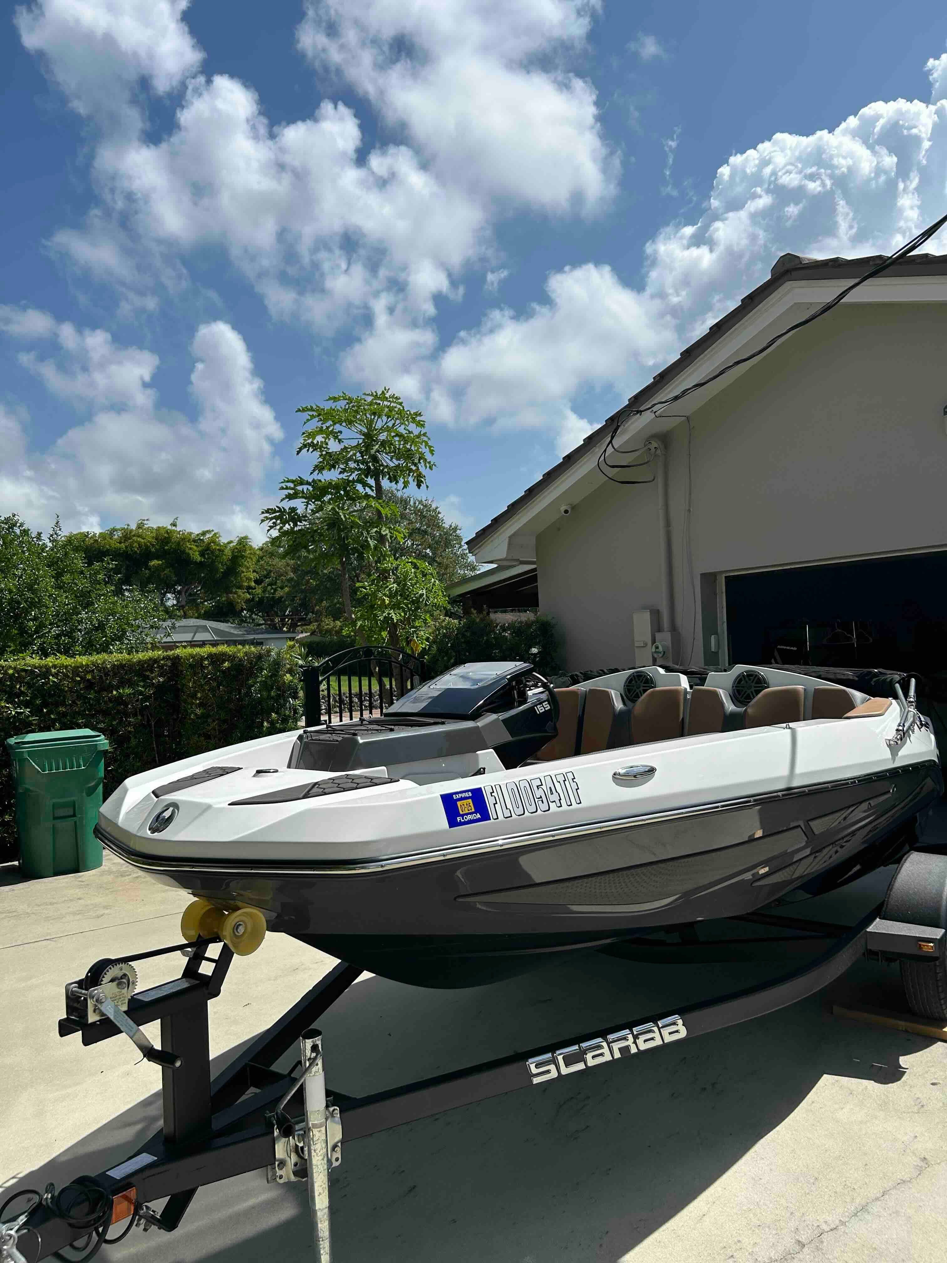 A 2022 Scarab 165 ID boat on a trailer in front of a house.
