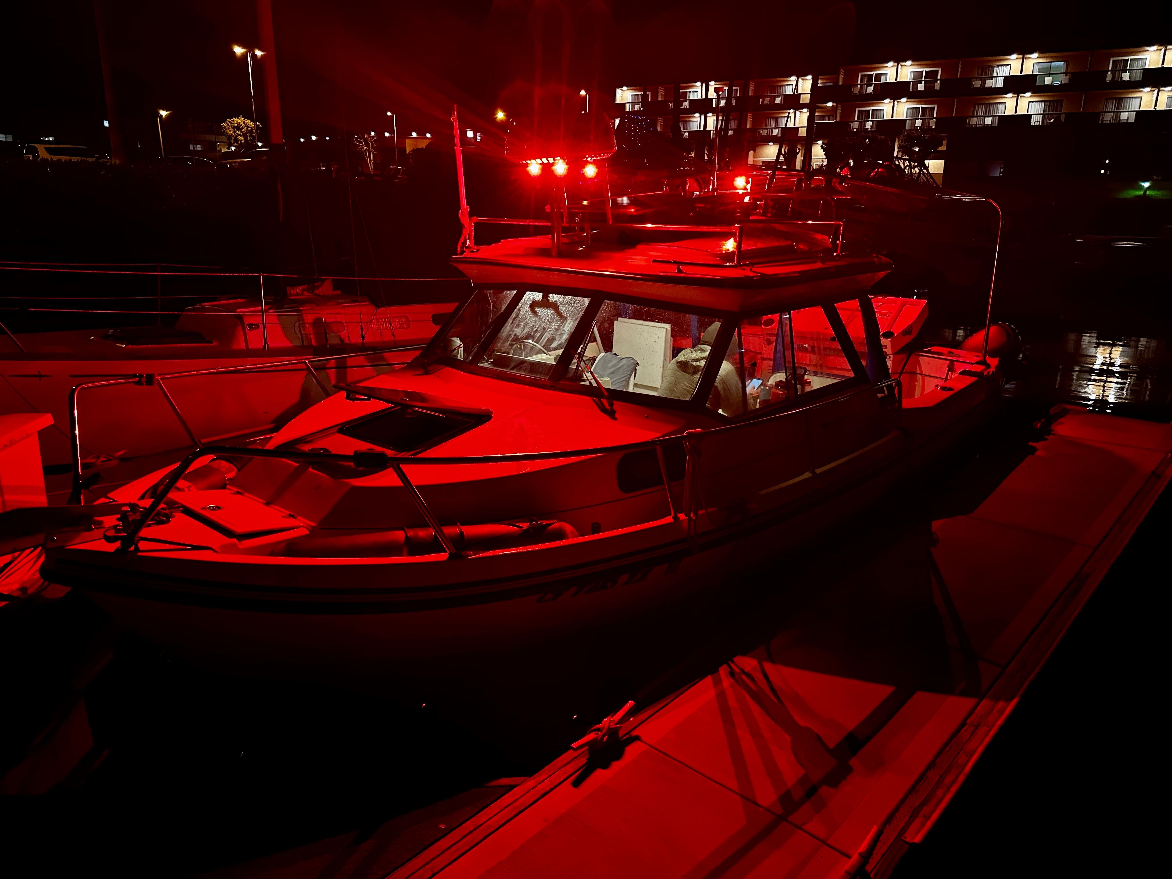 A 2003 Arima Sea Legend boat docked at night, illuminated by red lights.