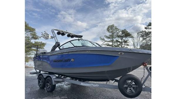2023 MasterCraft XT22 boat on trailer, blue and gray design, parked outdoors.