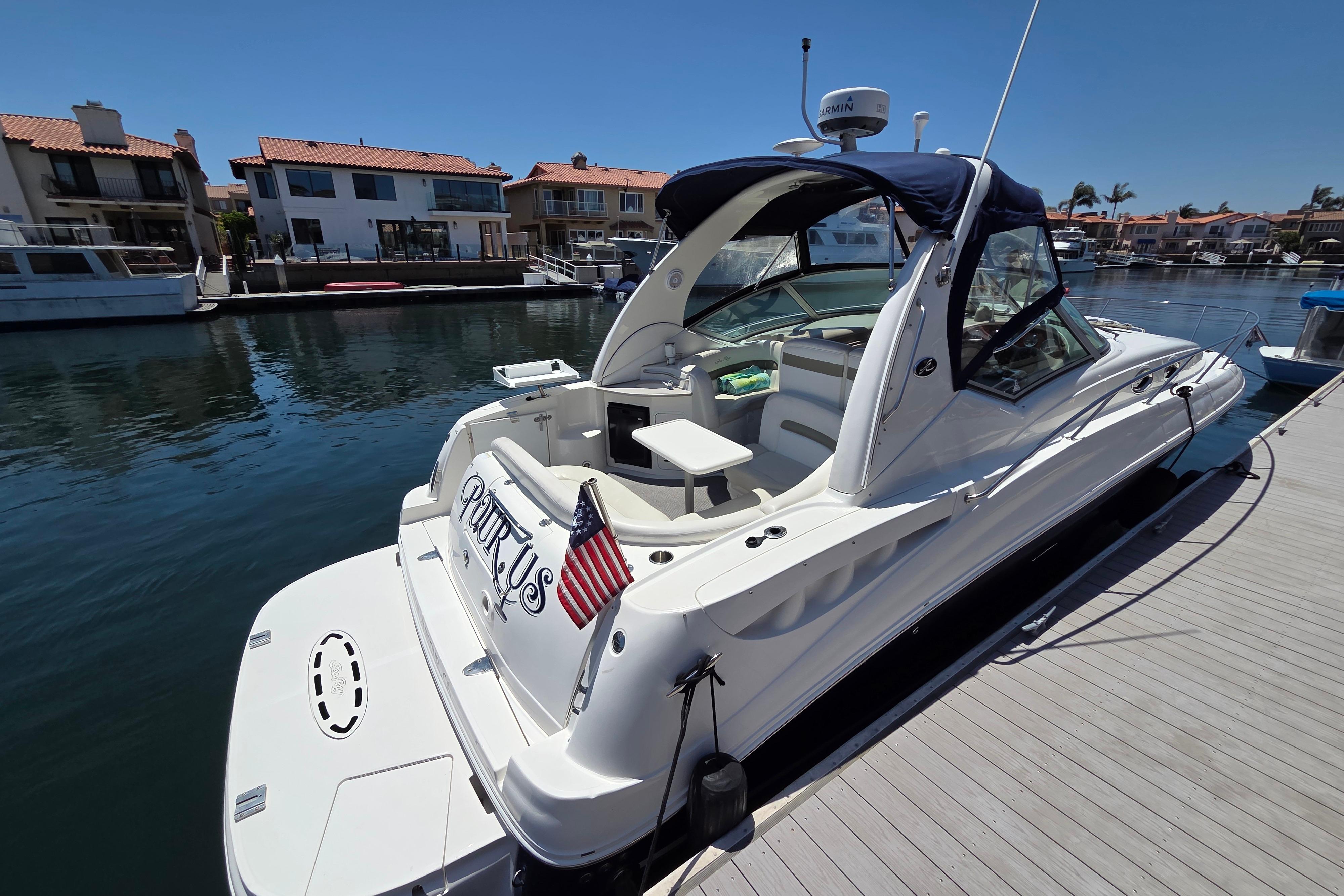 2006 Sea Ray Sundancer 320 docked in a marina, featuring sleek design and American flag.