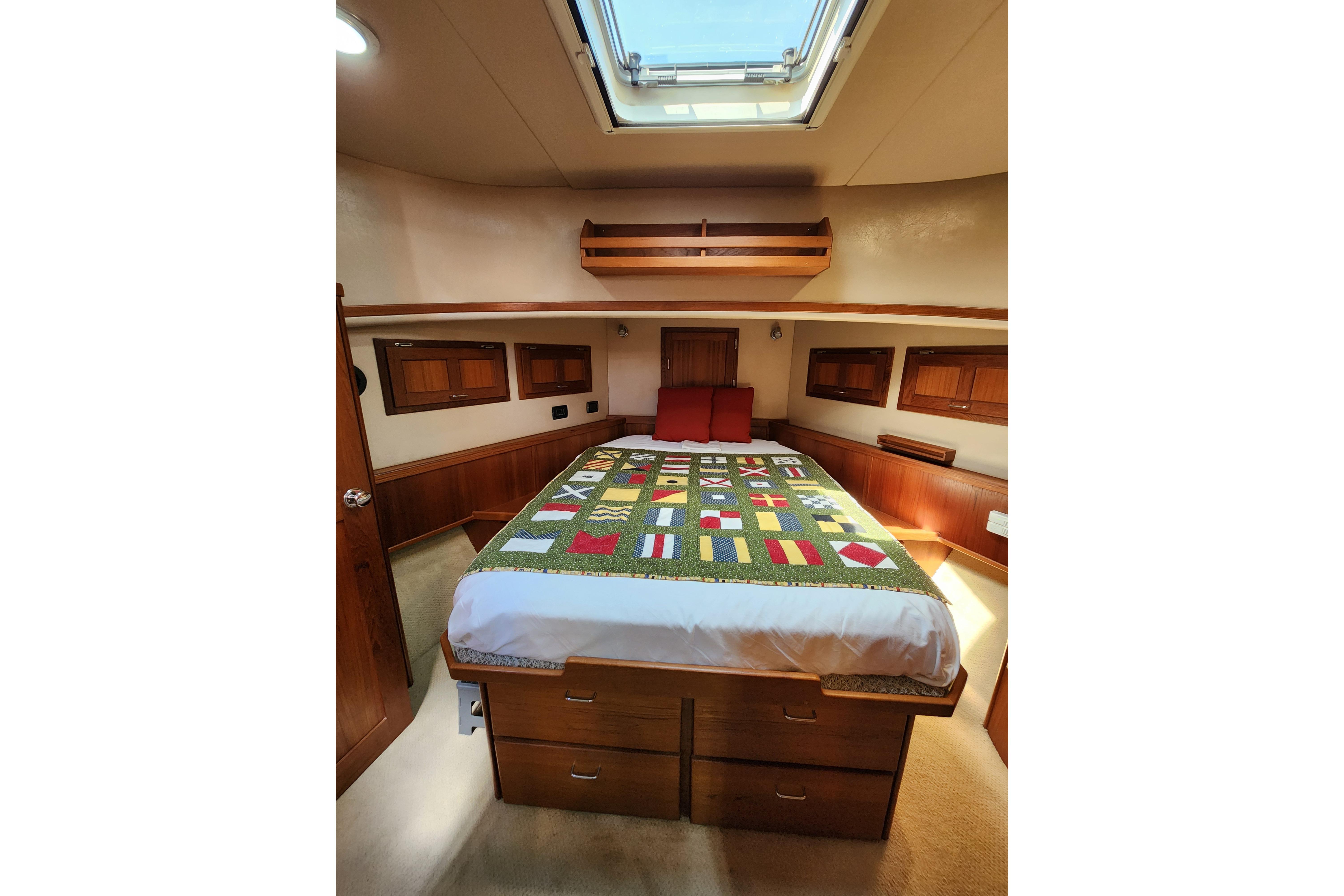 Cozy cabin interior of 2006 American Tug AT with nautical-themed bedding and skylight.