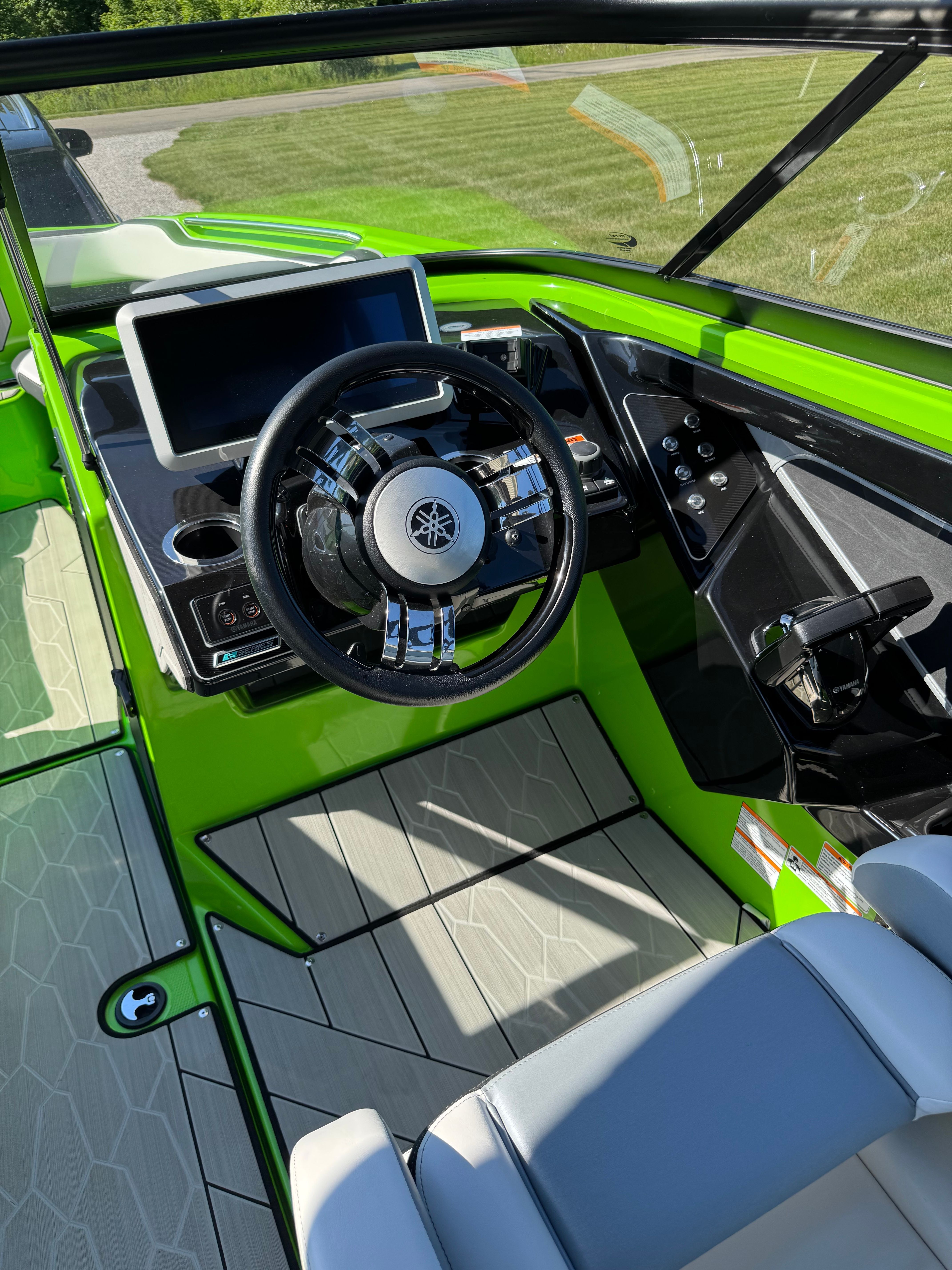 The image shows the cockpit of a 2022 Yamaha Boats 255XD with a modern steering wheel and large screen.