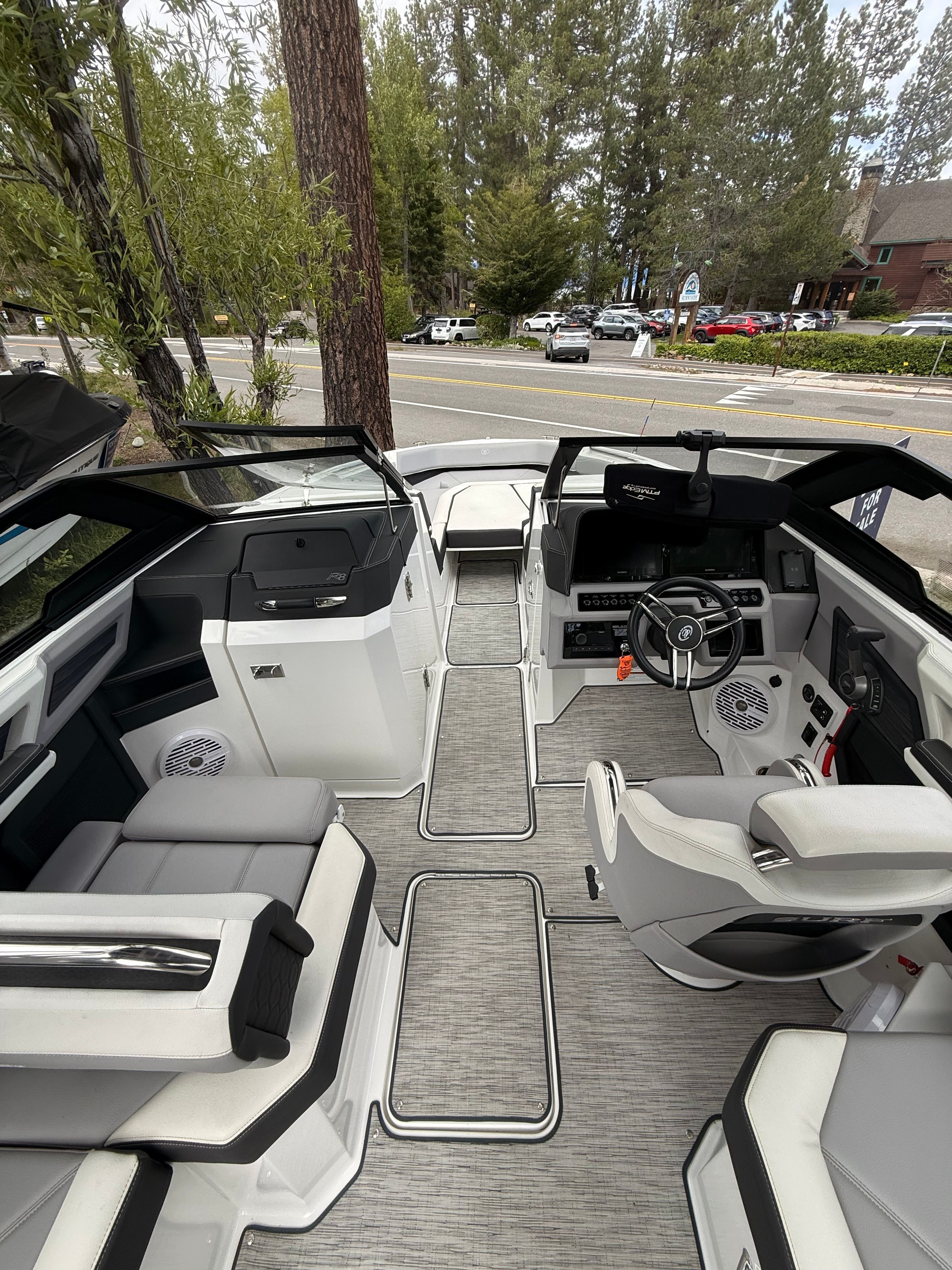 Interior view of a modern boat with gray and white seating, steering wheel, and control console.