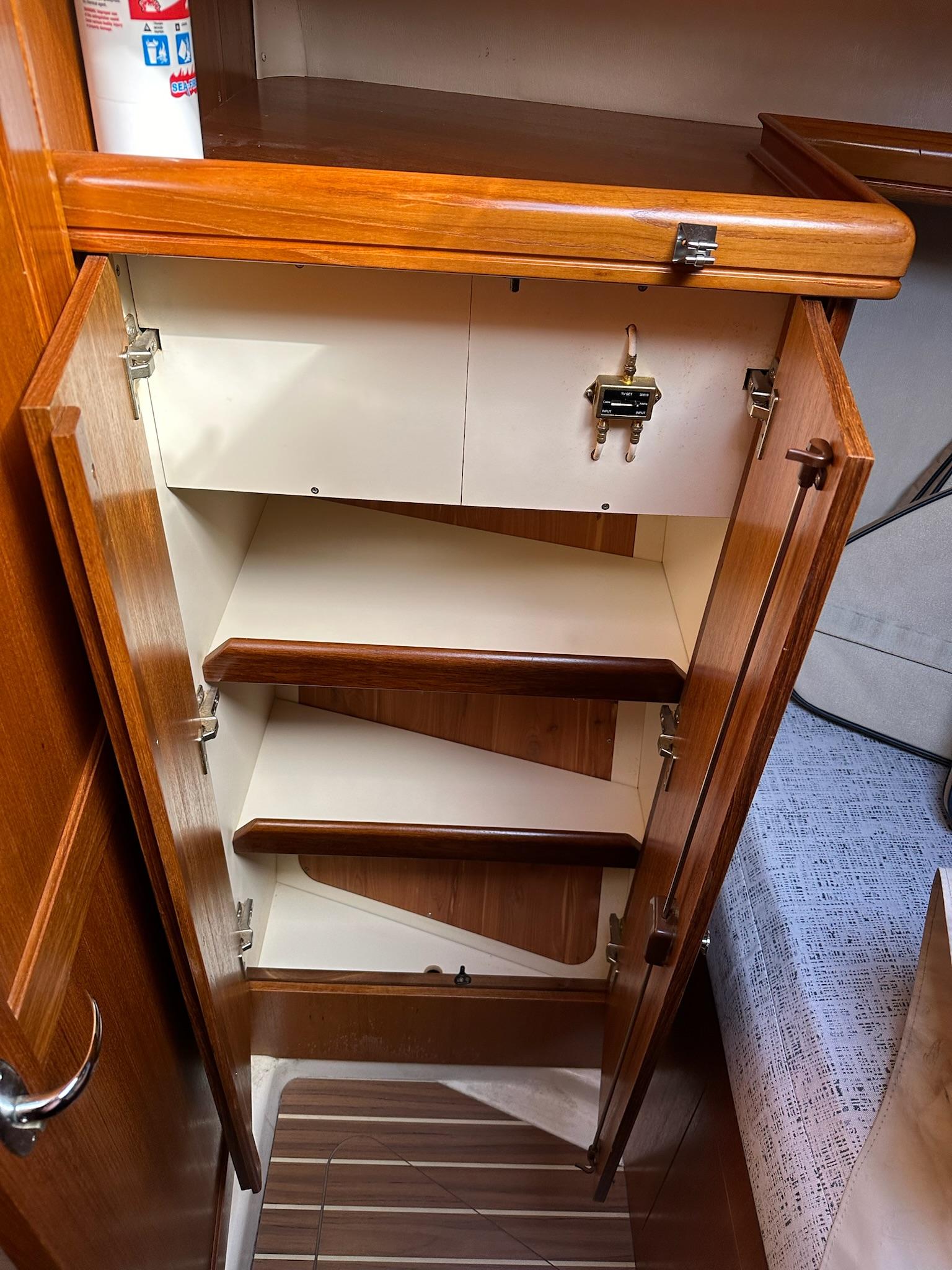 2005 Hunter 38 sailboat interior cabinet with wooden shelves and secure latch.