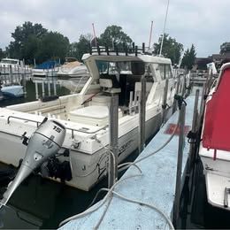 A 2001 Sport-Craft 272 boat docked, featuring an outboard motor and a spacious deck.