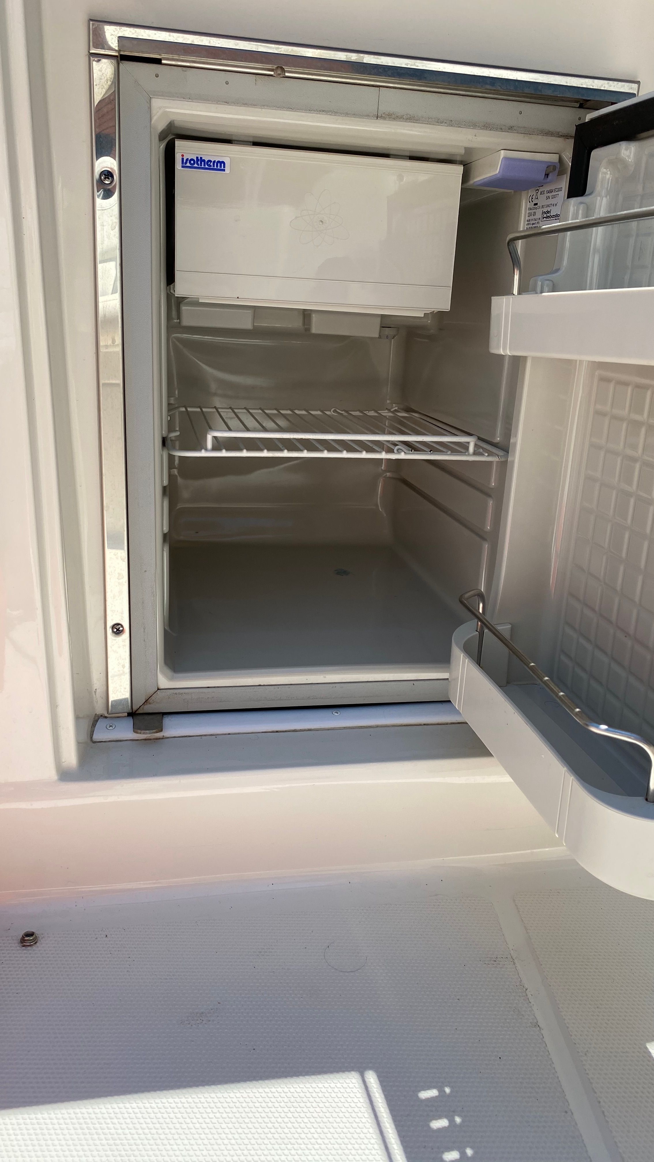 An open fridge on a boat with empty shelves.