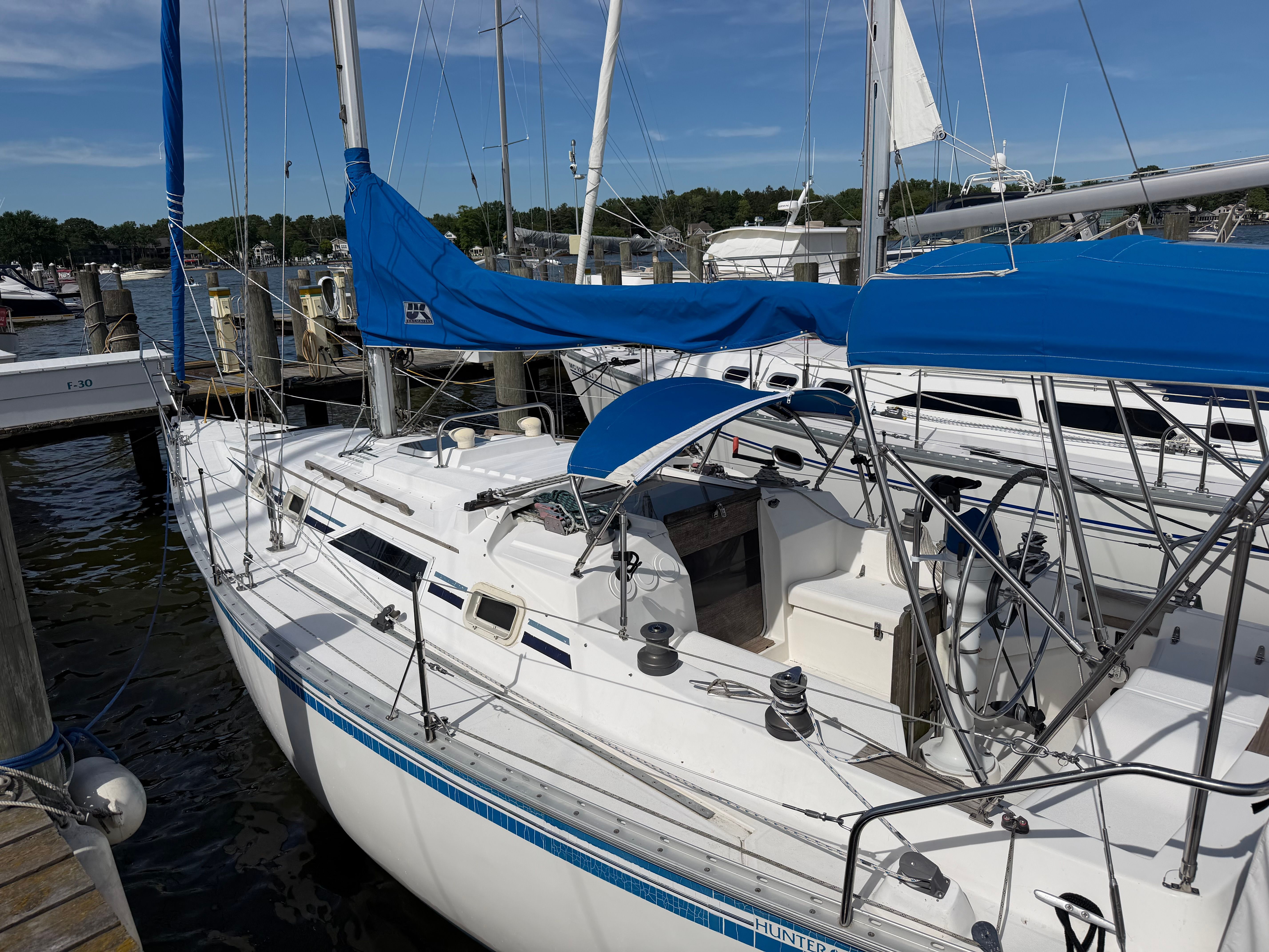 A white sailboat with blue covers docked at the marina.