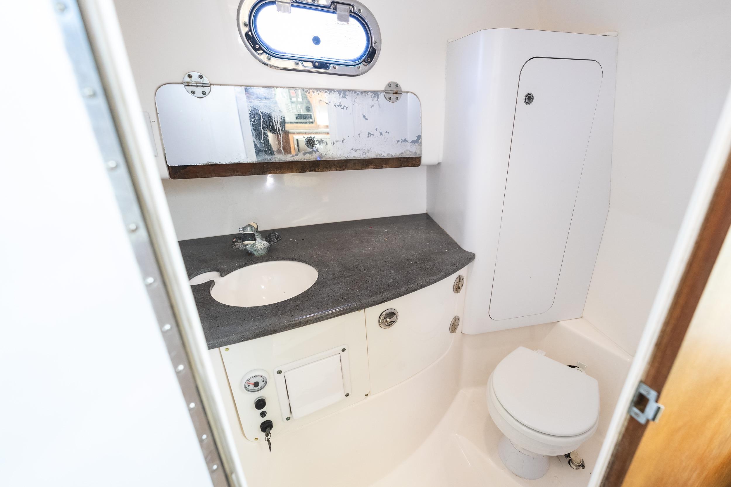 Compact boat bathroom with sink, mirror, and toilet in 2011 Everglades 350EX model.