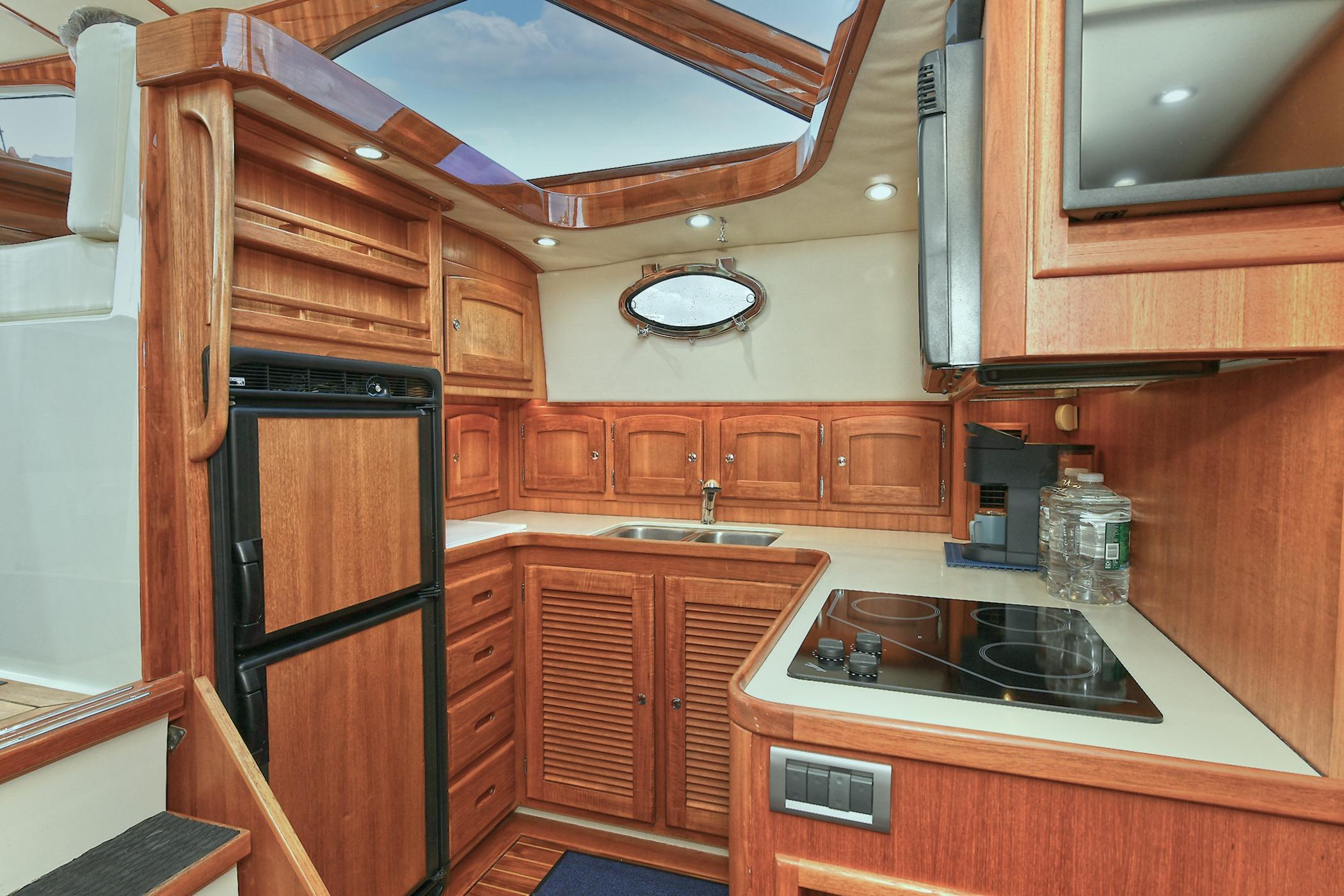 Luxurious 2005 San Juan Downeast Express yacht kitchen with wood cabinetry and modern appliances.
