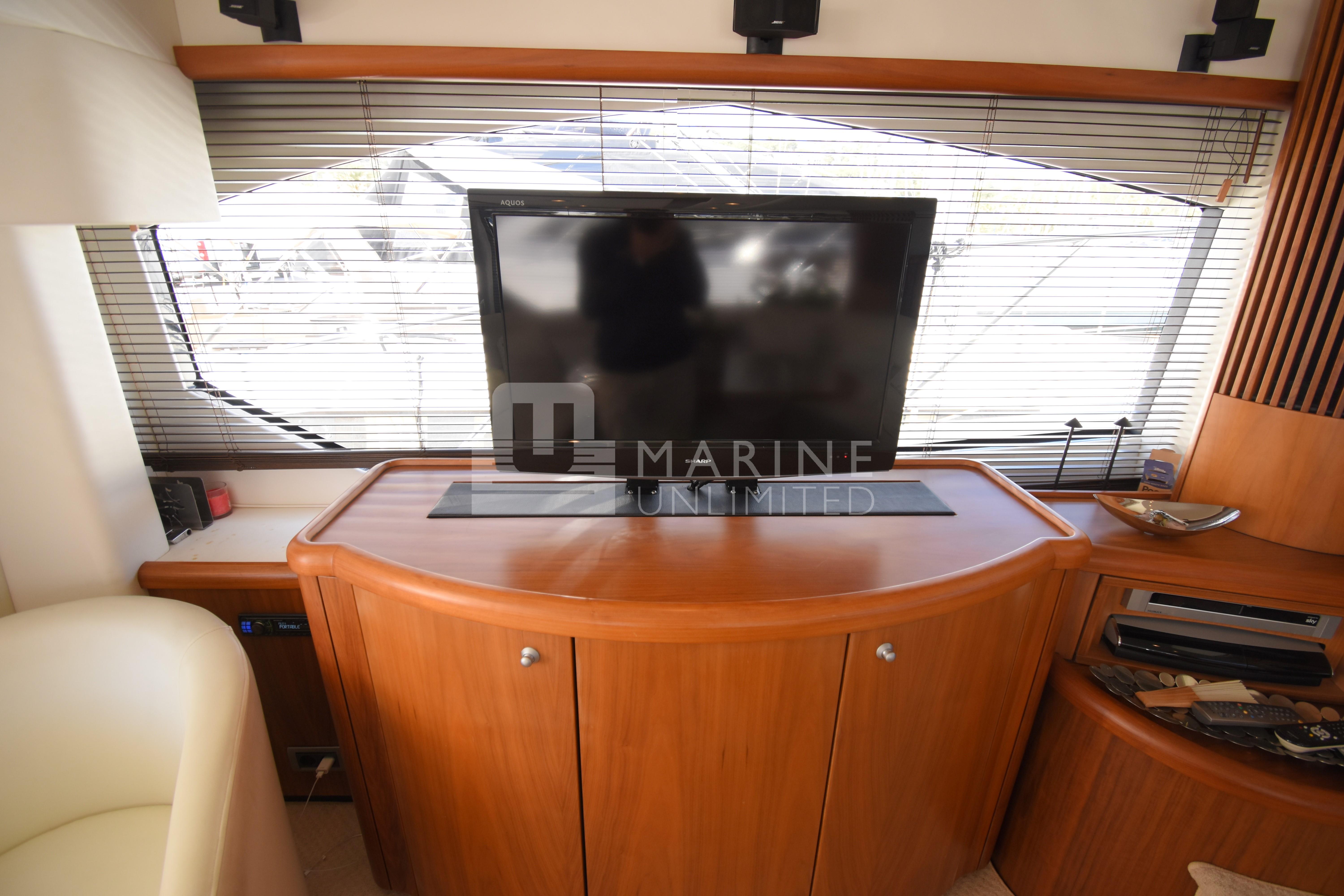 Luxurious interior of 2010 Sunseeker Manhattan 52 yacht with TV and wooden cabinetry.