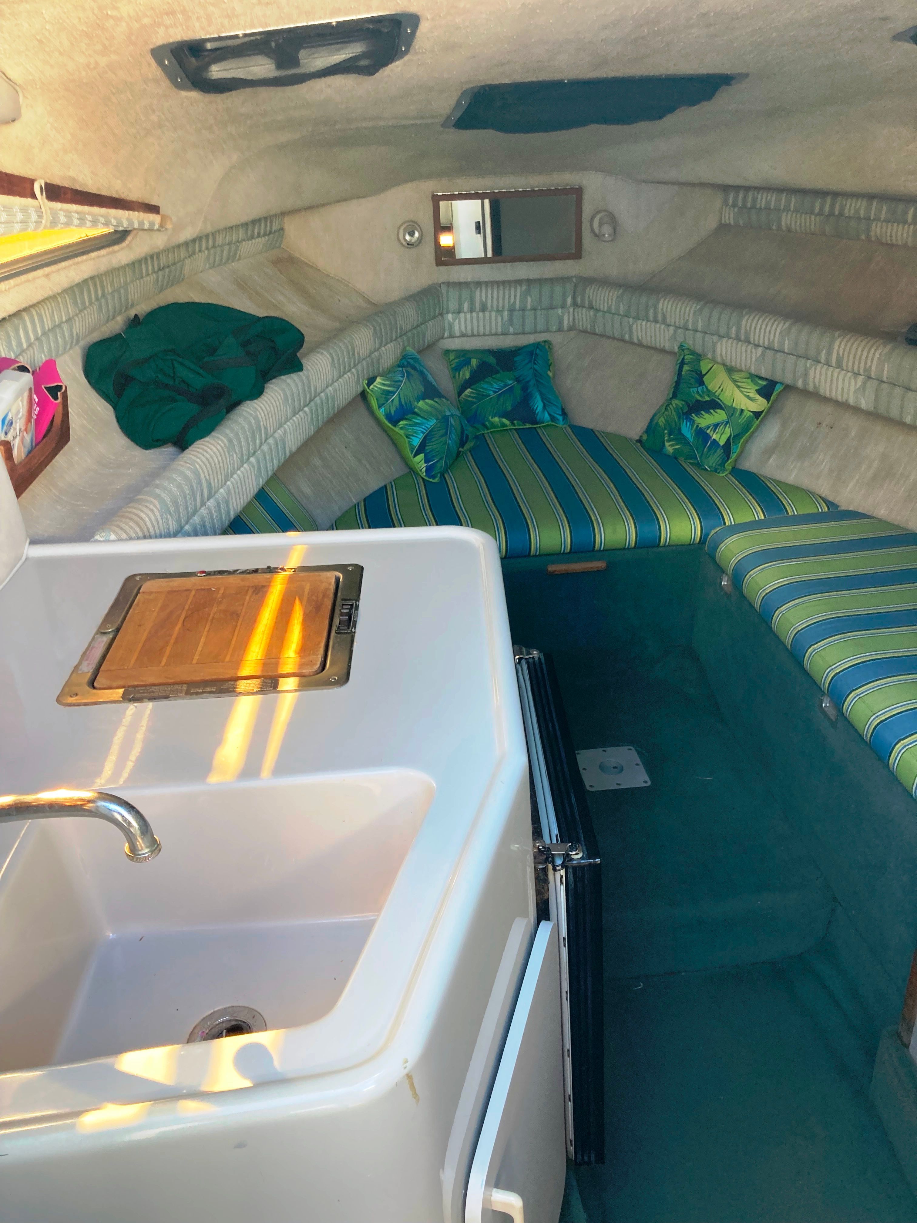 Interior of a 1991 Sea Ray 220 Sundancer with a kitchenette and seating area.
