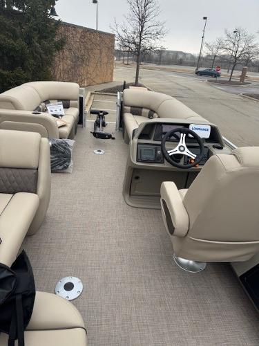 2025 Sun Tracker SportFish 22 DLX pontoon boat interior with beige seating and steering console.