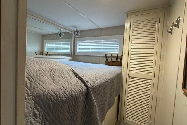 Cozy bedroom in 1997 Stardust Houseboat 18x83 with quilted bedding and louvered closet.