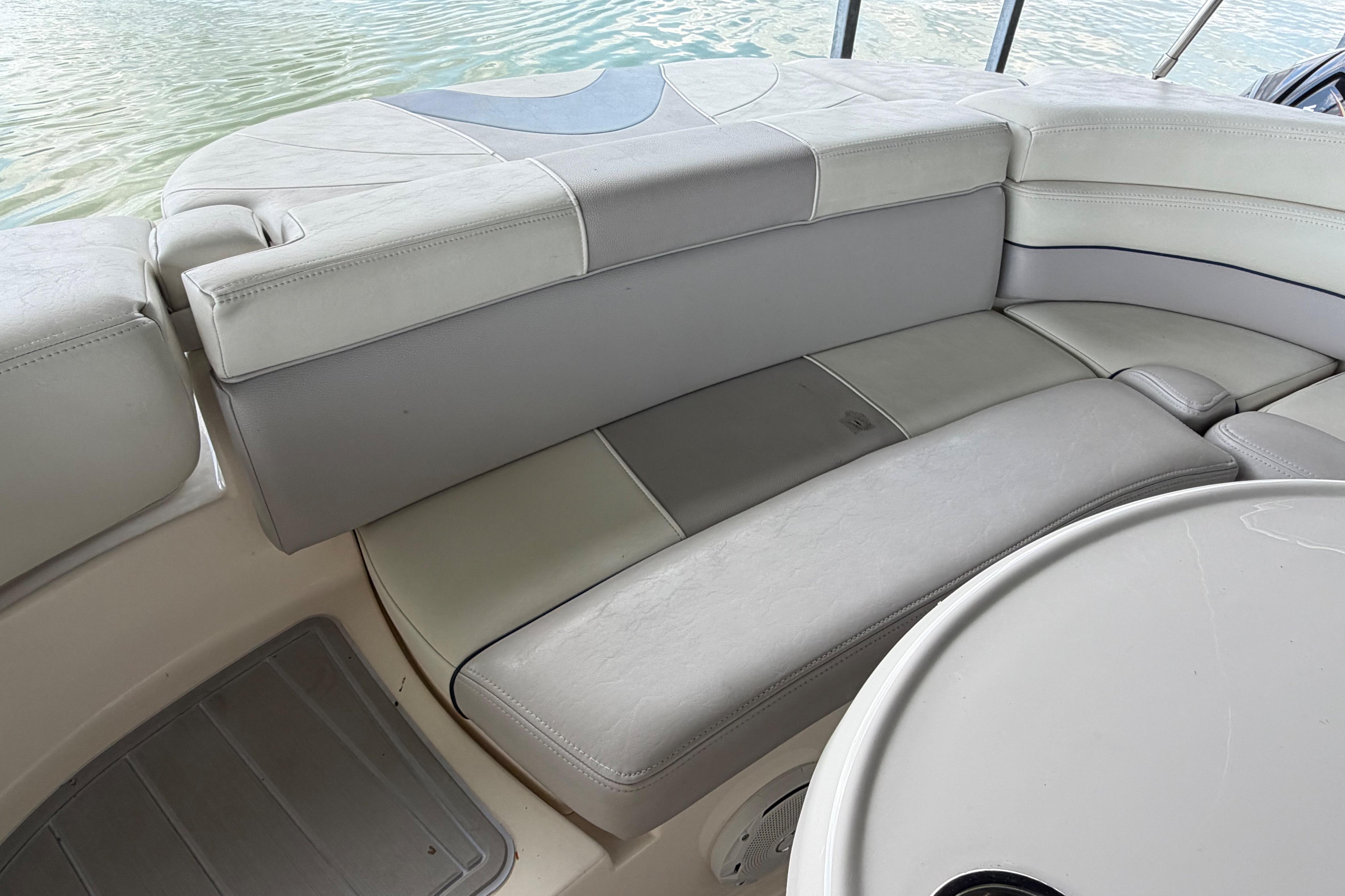 2010 Bryant 255 boat interior with cushioned seating and table, near water.