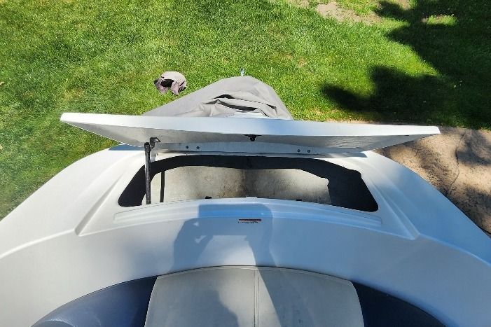 An open storage compartment on a boat, surrounded by green grass.