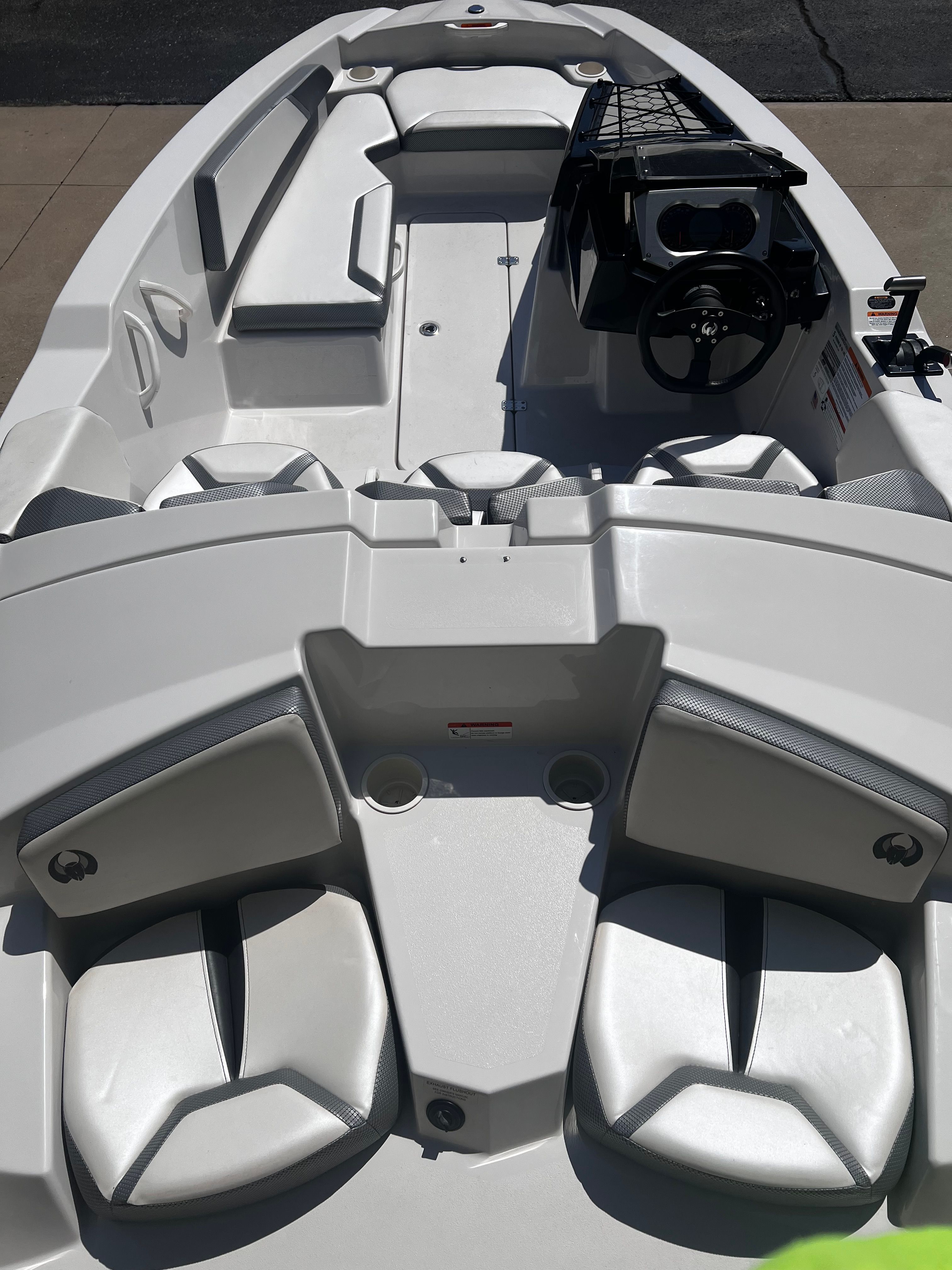 A white motorboat with seating and a steering console.
