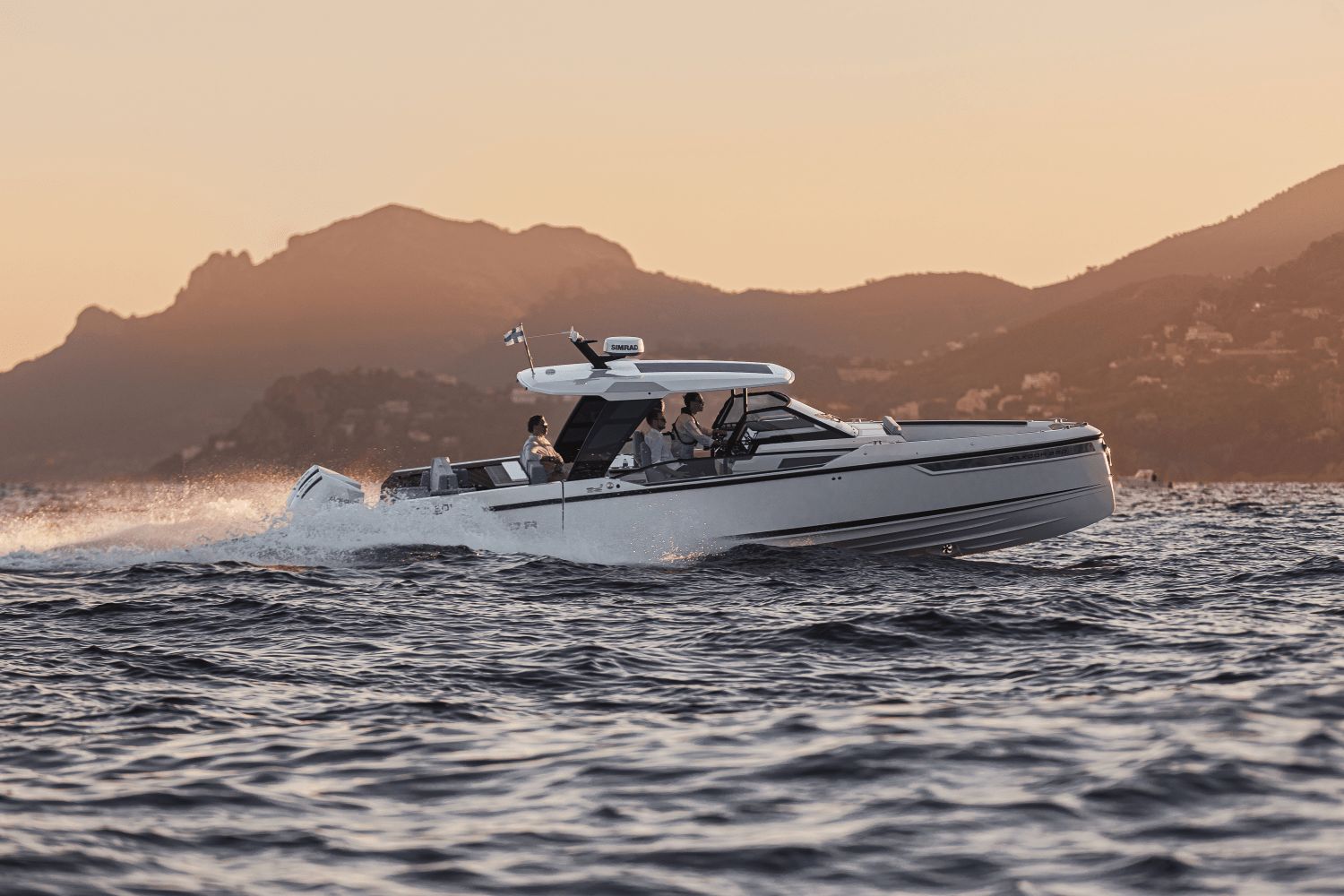 A Saxdor SX320 GTO boat cruising on the water at sunset, surrounded by mountains.