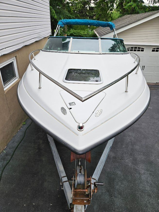 A 1998 Crownline 210 CCR boat on a trailer in a driveway.