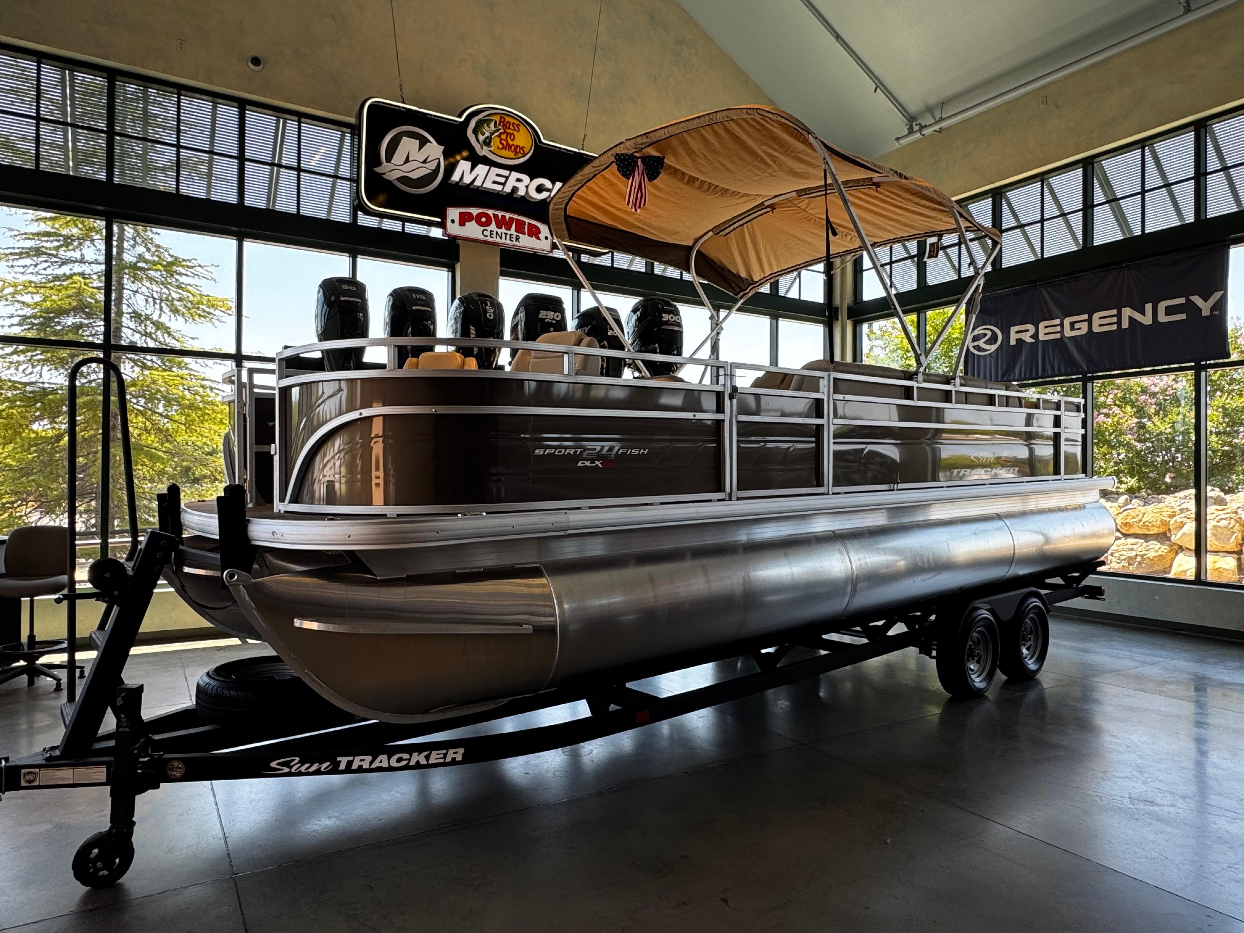 2025 Sun Tracker Sportfish 24 XP3 pontoon boat displayed indoors on a trailer.