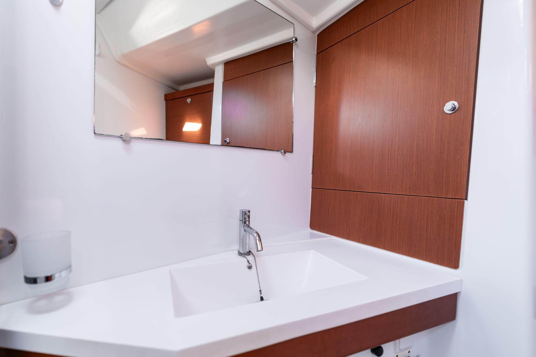Modern bathroom interior on 2013 Beneteau Oceanis 50 yacht, featuring sleek sink and wooden cabinetry.