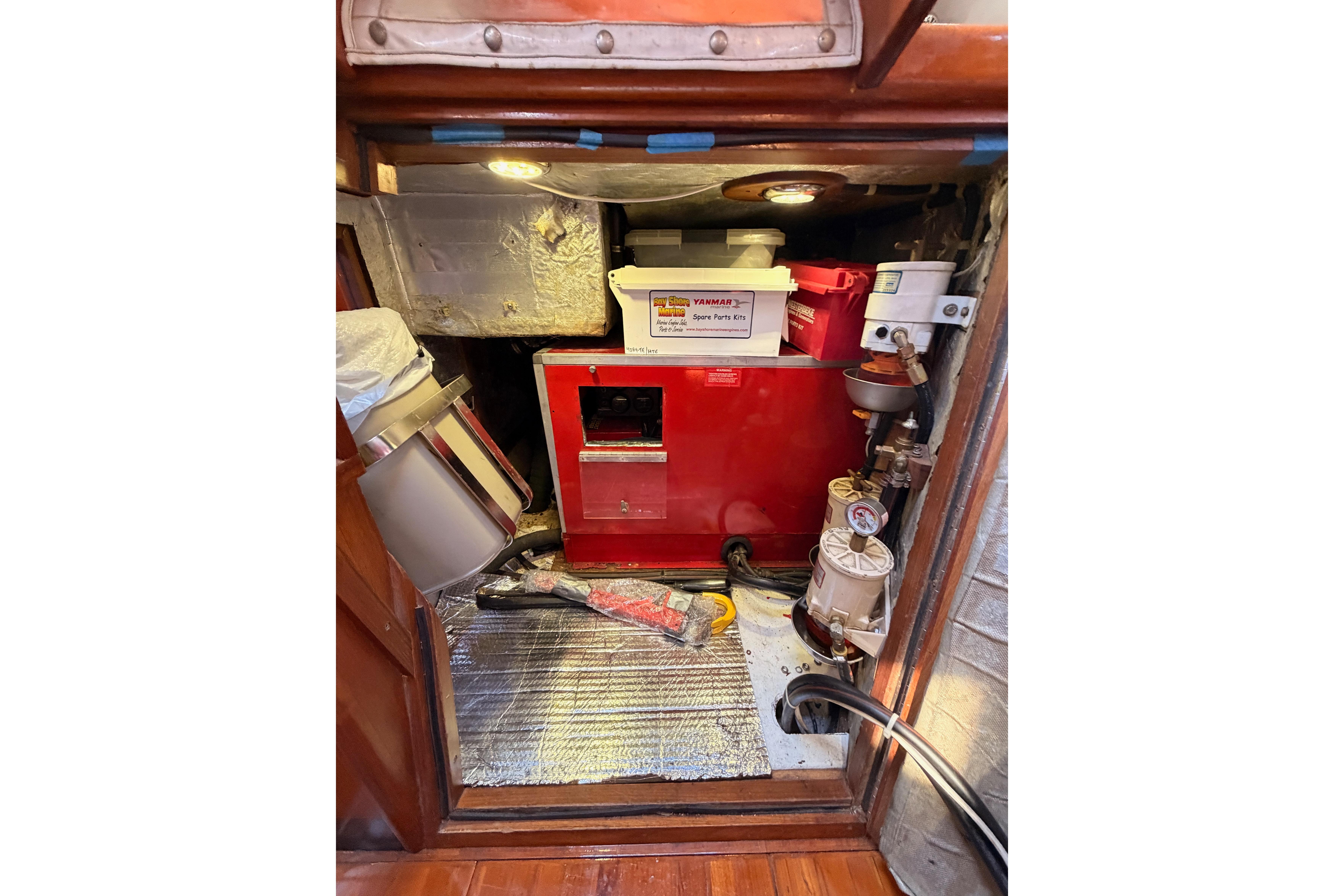 Engine compartment of a 1991 Hylas 51 yacht with spare parts and tools.