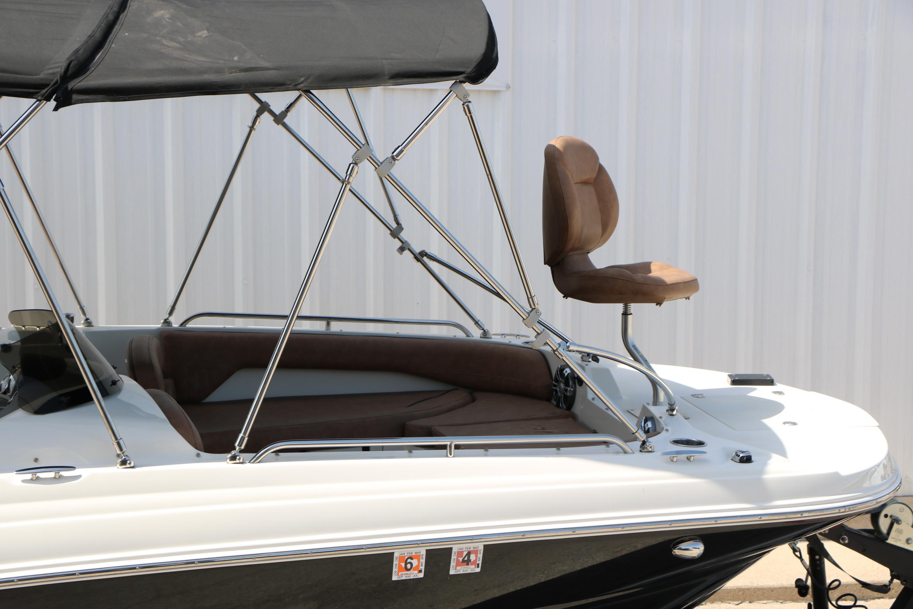 2022 Stingray 192 SC boat with brown seating and canopy, docked near a white wall.
