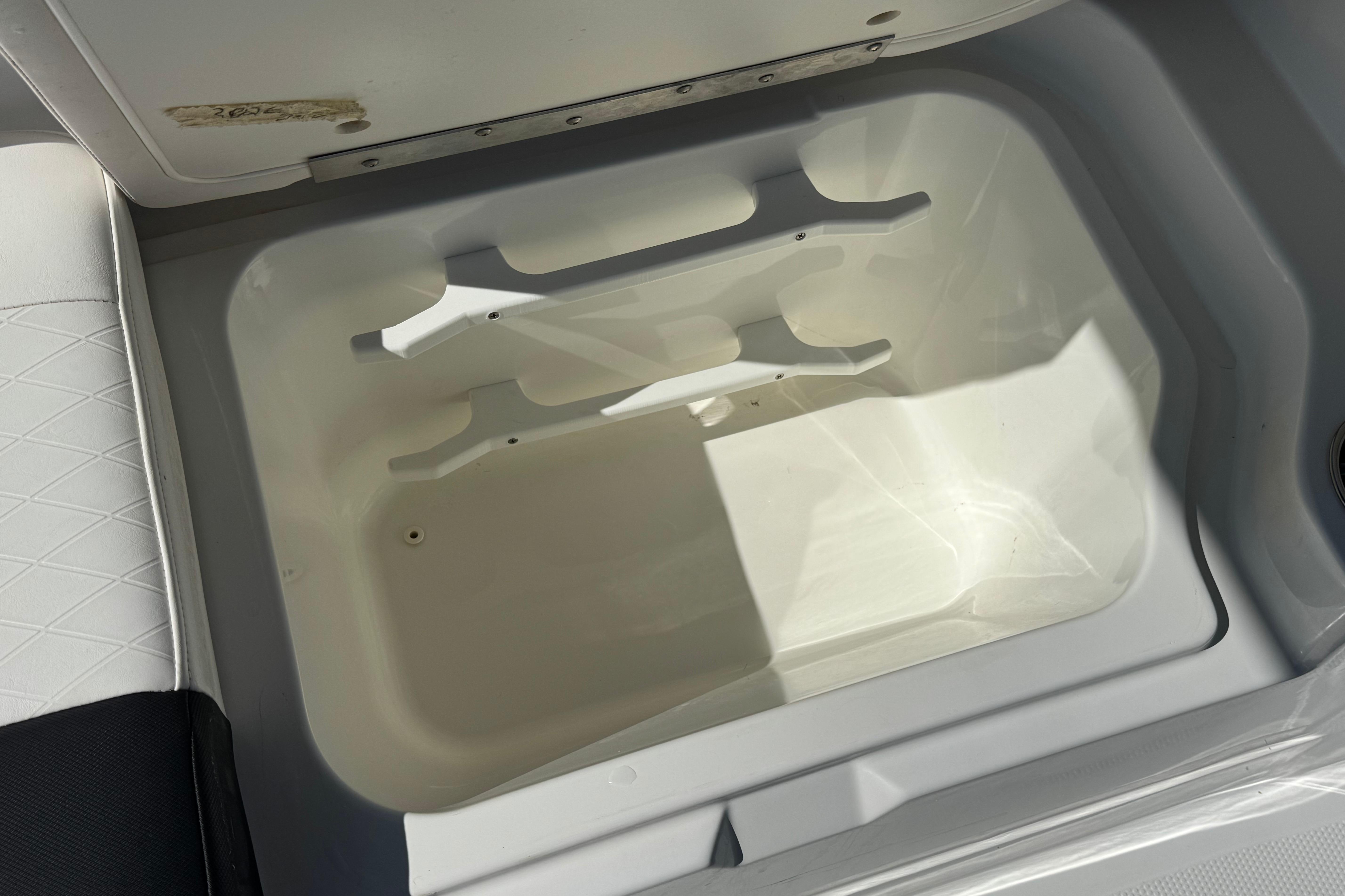 Open storage compartment in a 2019 Tahoe 2150 boat, featuring white interior.
